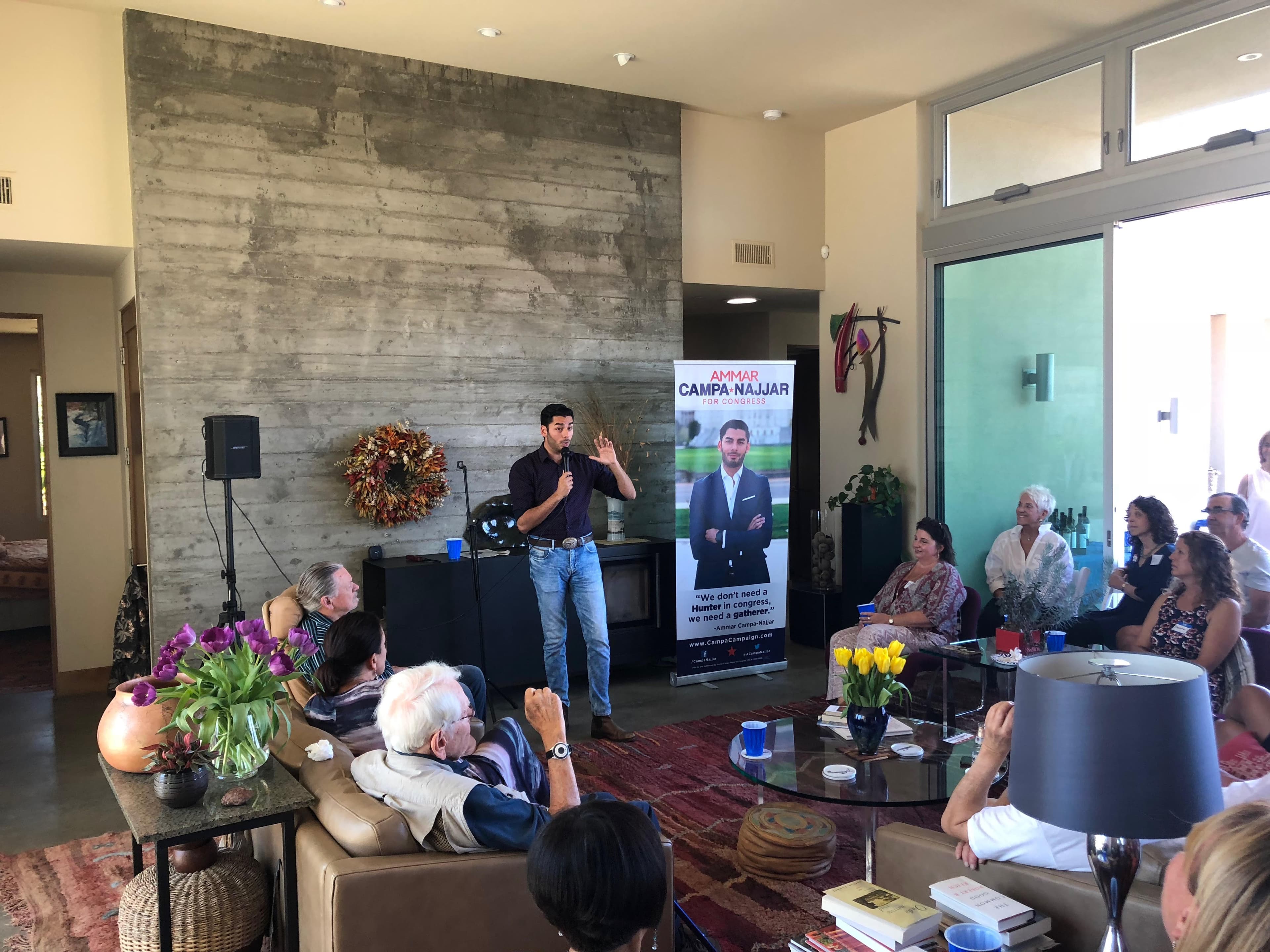 Man standing in airy living room, speaking to small group seated around him