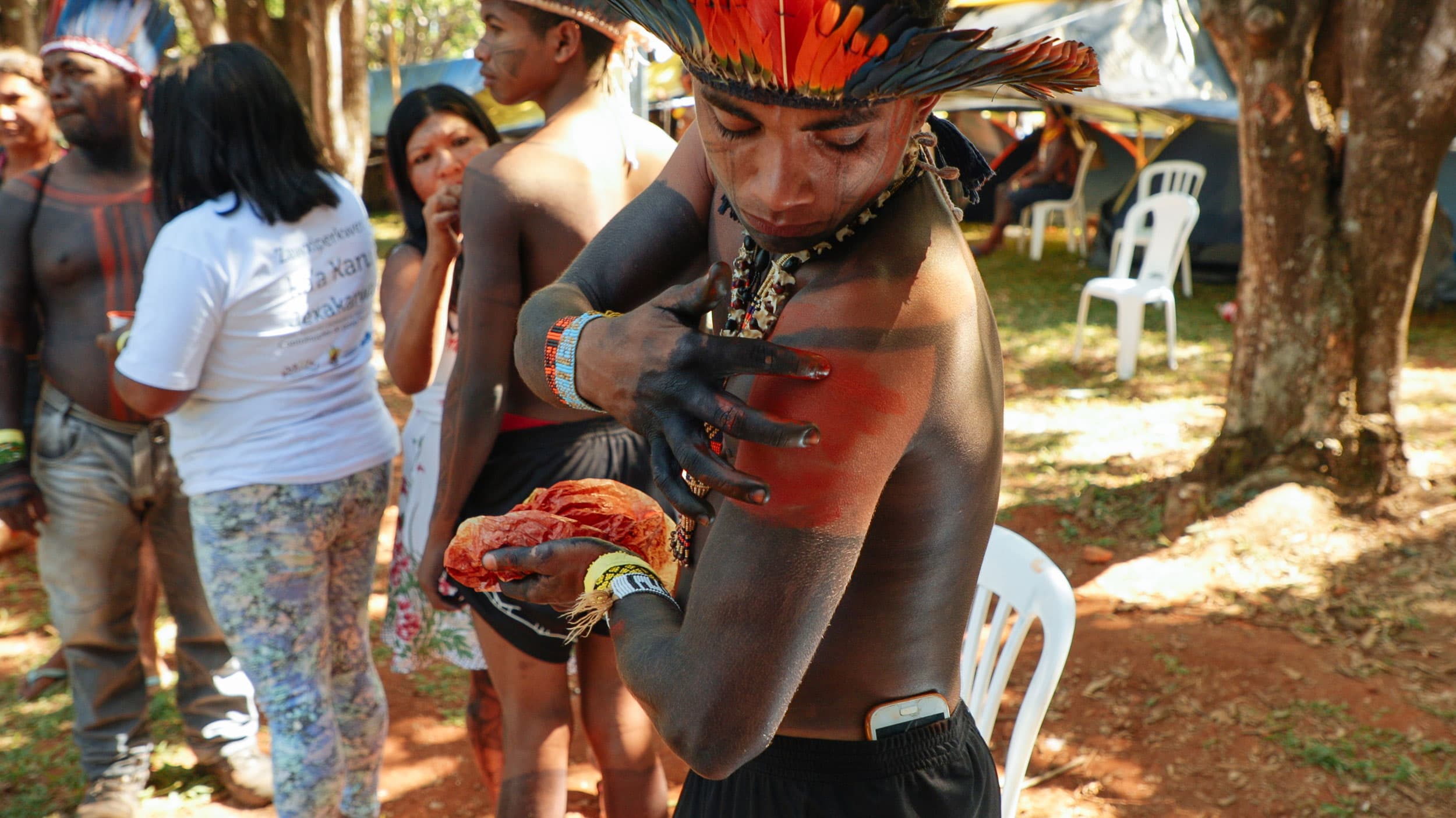 A young man rubs red paint on his body