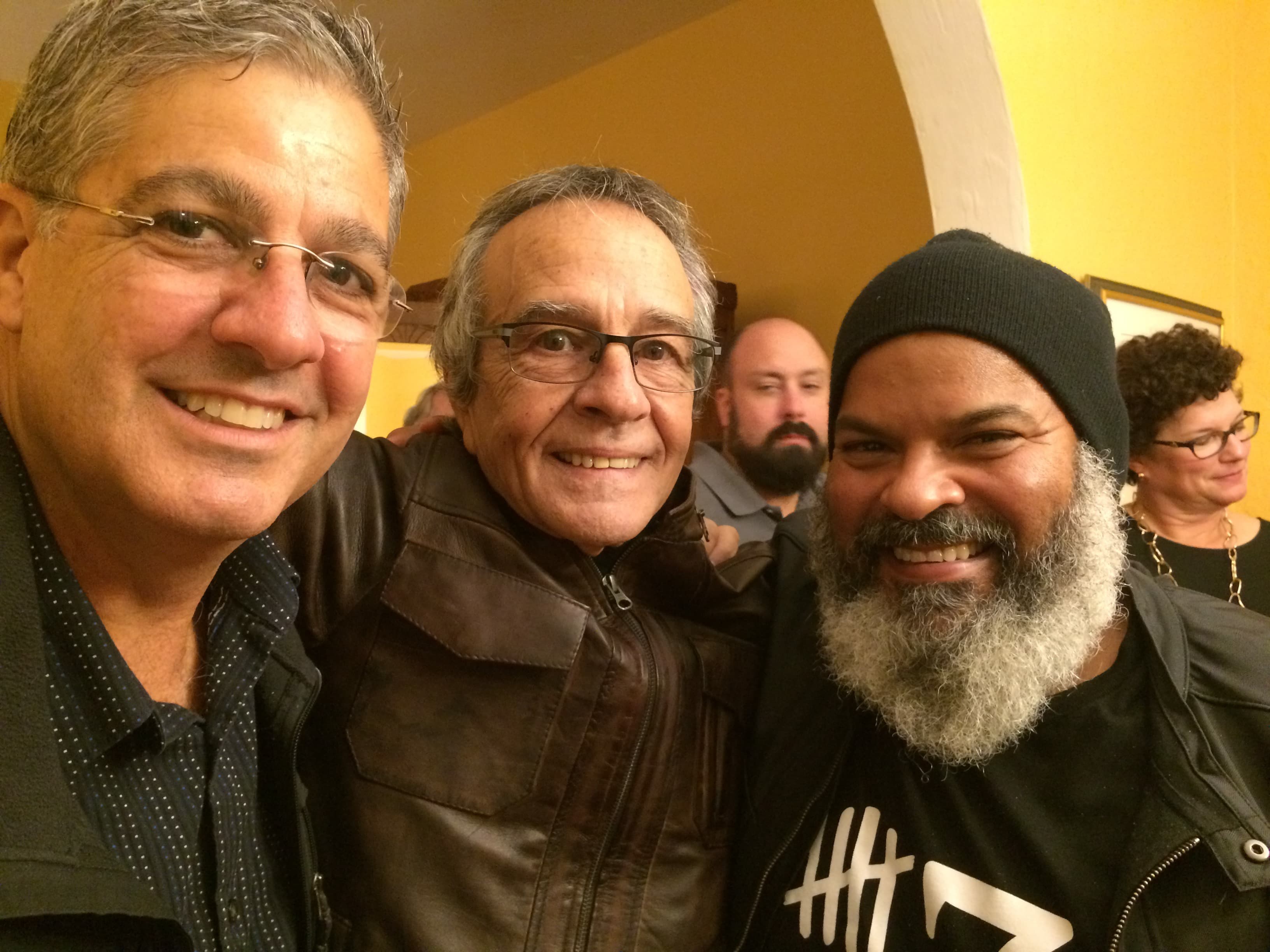 Three men lined up, posing for the camera