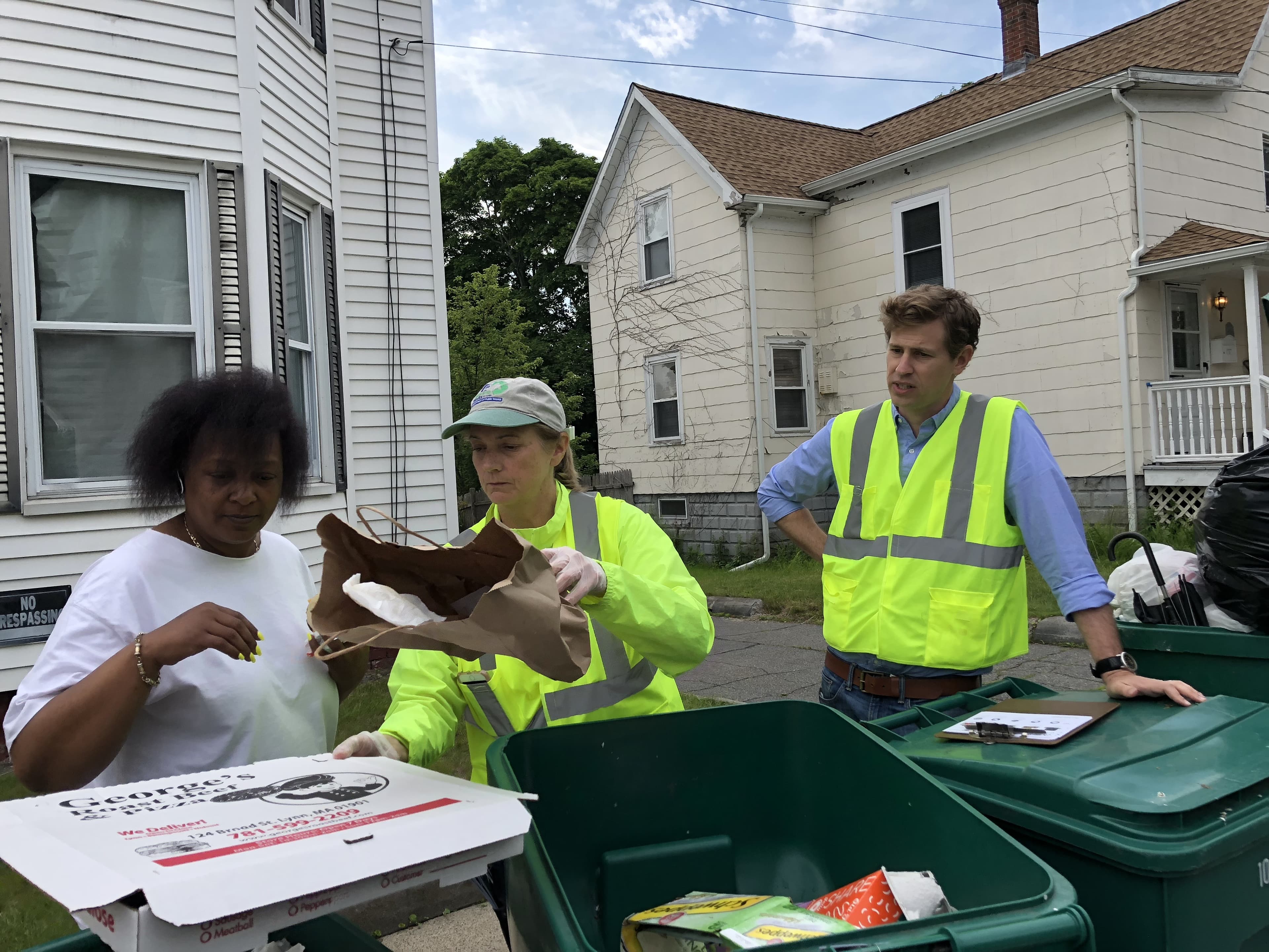 Julia Greene (center), the recycling coordinator for the city of Lynn, Mass., gives resident Diane Thomas (left) a brief tutorial on recycling. Cody Marshall, with the Recycling Partnership, looks on, offering words of encouragement.