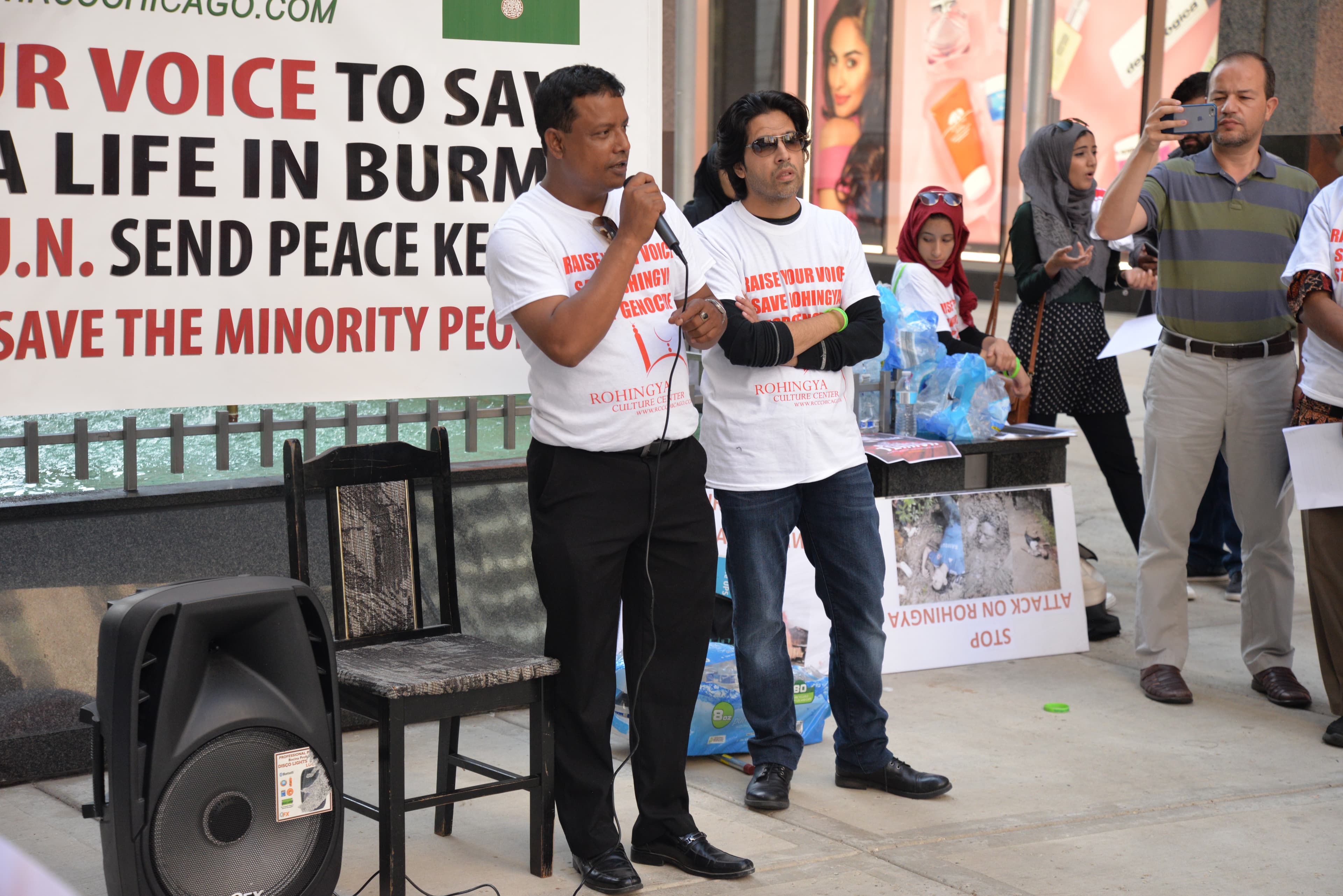 A man holding a microphone addresses the crowd during a protest in downtown Chicago.