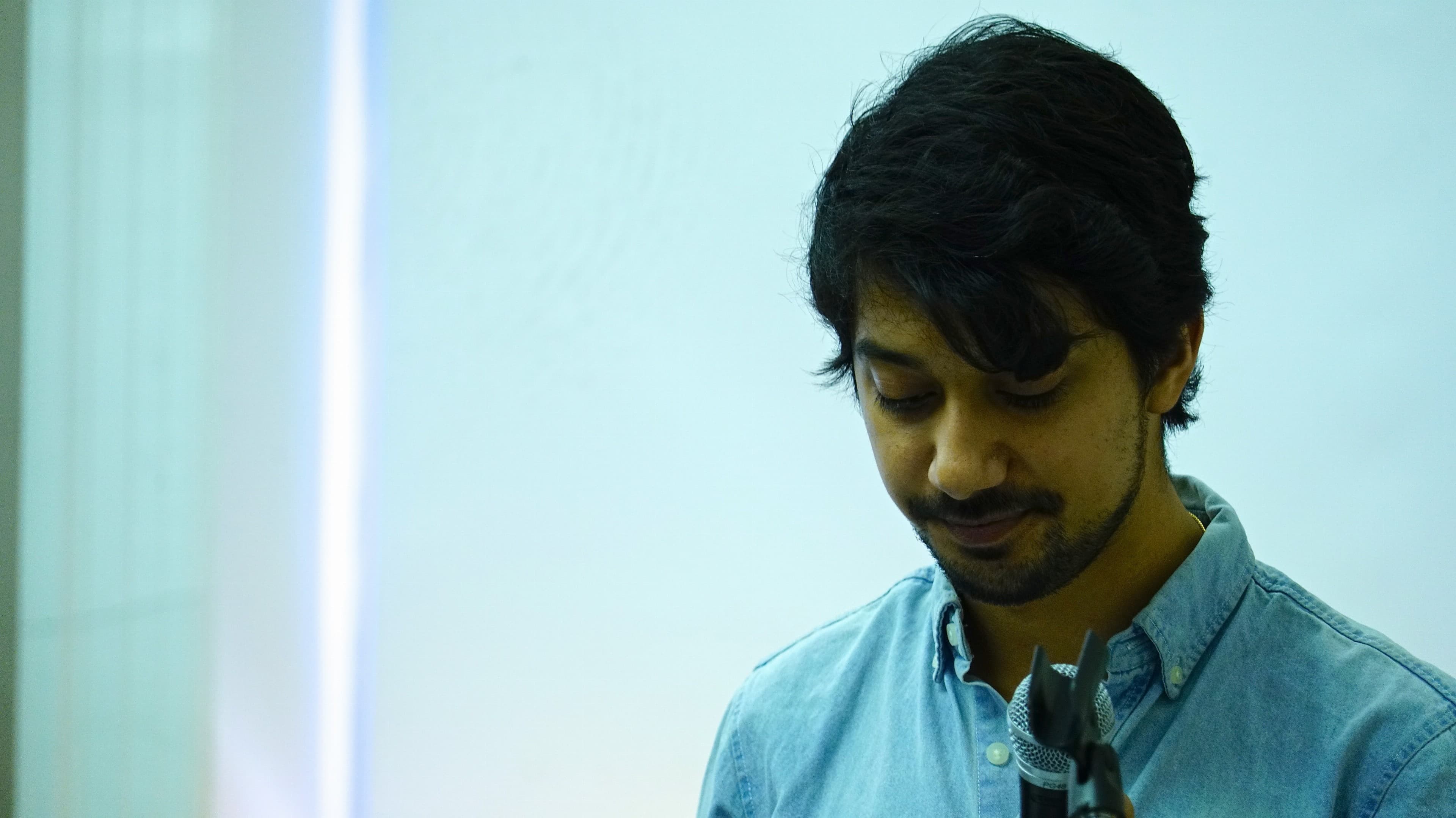 Man on right side of image, looking down with blue screen behind him