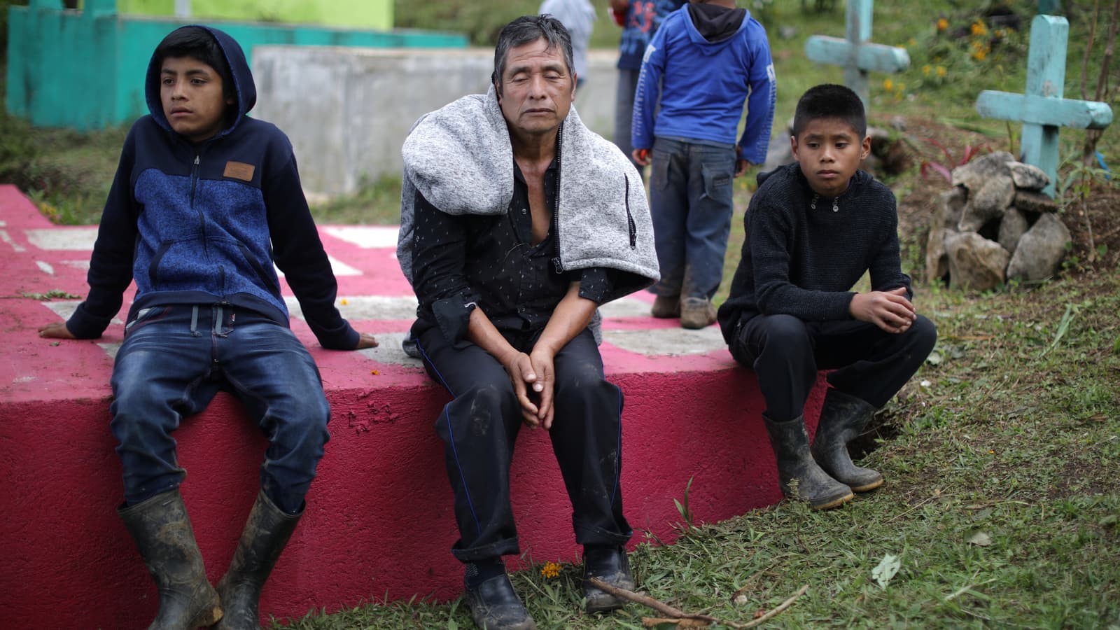 Miguel Paiz Domingo sits on the cement tomb of his son, Misael Paiz.