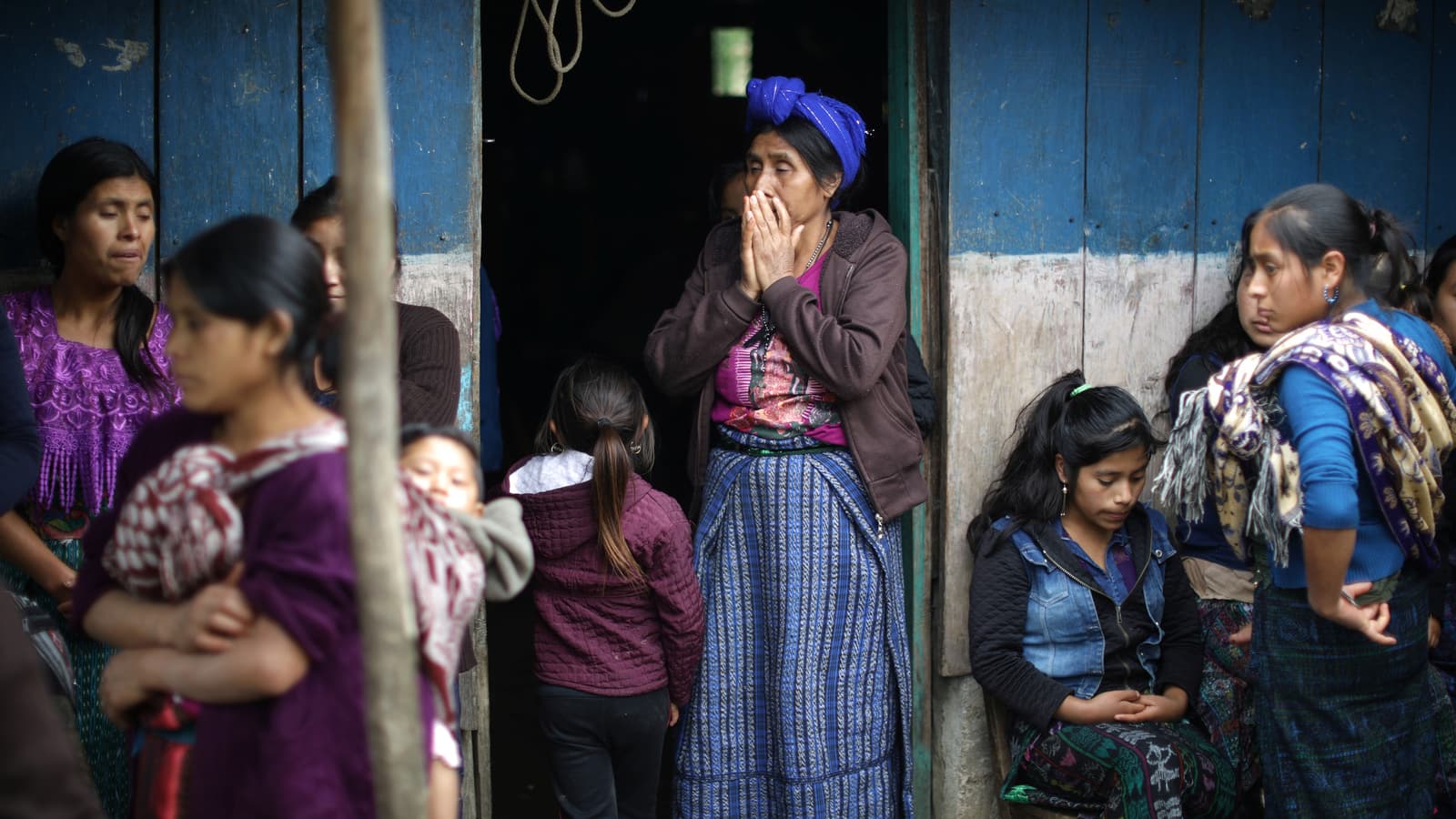 A woman stands in the doorway, covers her hand in shock.