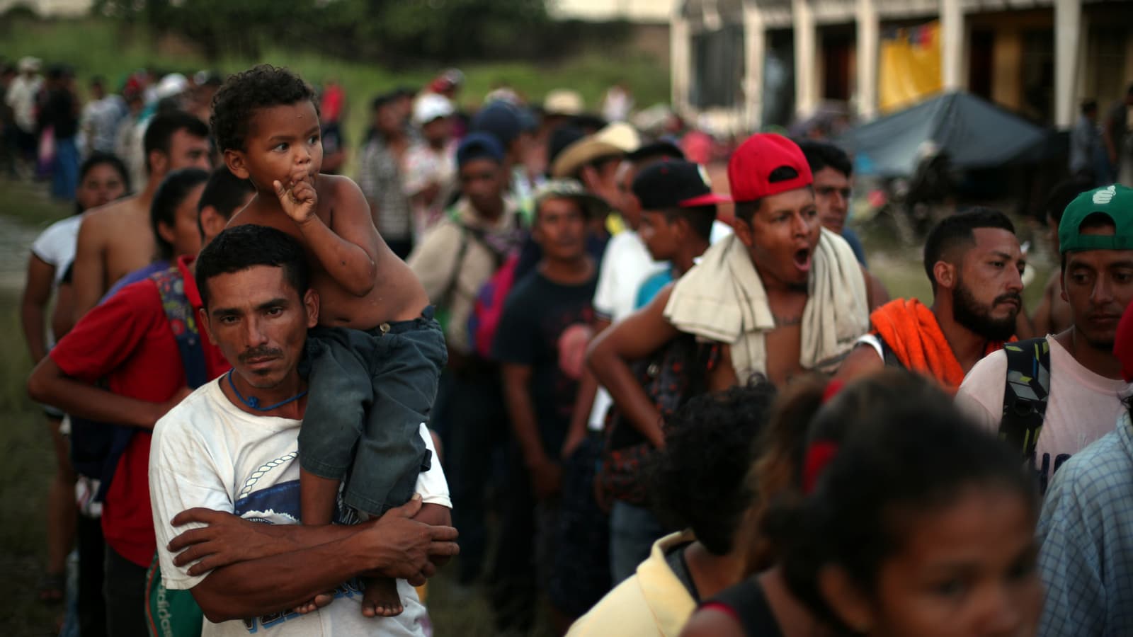 A large group of male migrants from Central America stand in line for food donations