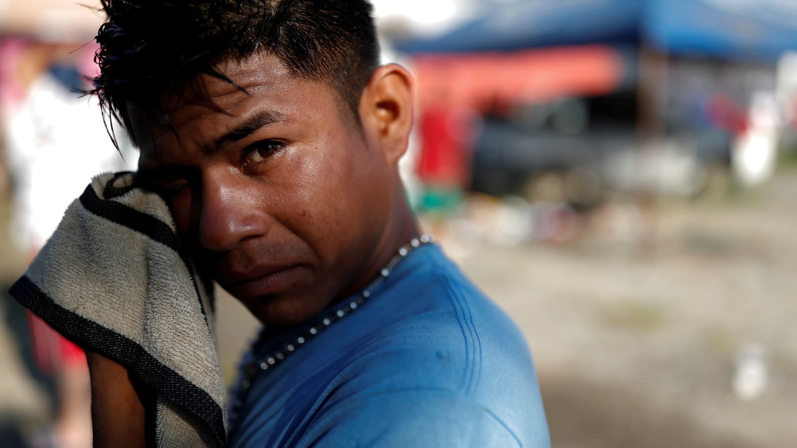A young man washes his face with a washcloth.
