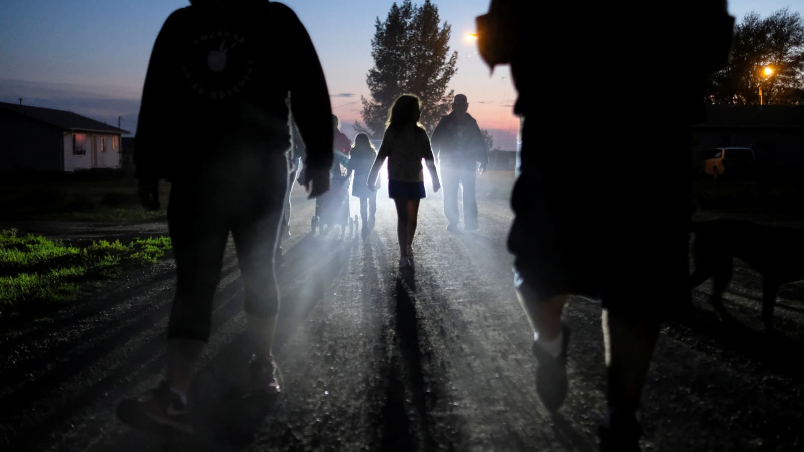 Shadowy figures walk down a dark street.