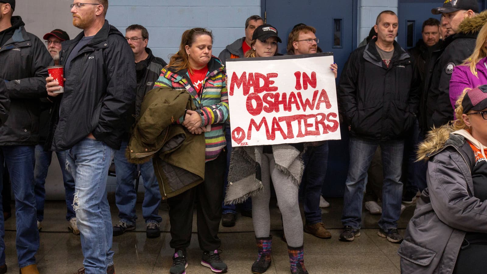 A GM worker in Canada holds a sign in red letters.