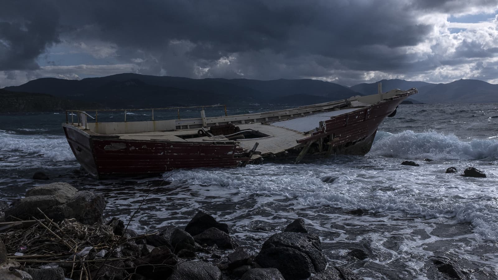 A tattered boat on the sea under stormy skies.