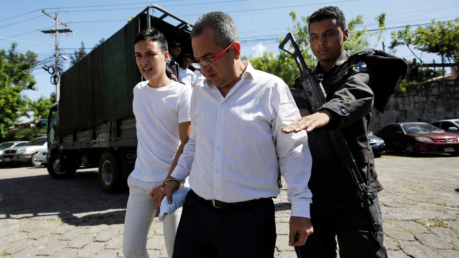 Two detainees dressed in white shirts and black pants arrive to court for their trial.