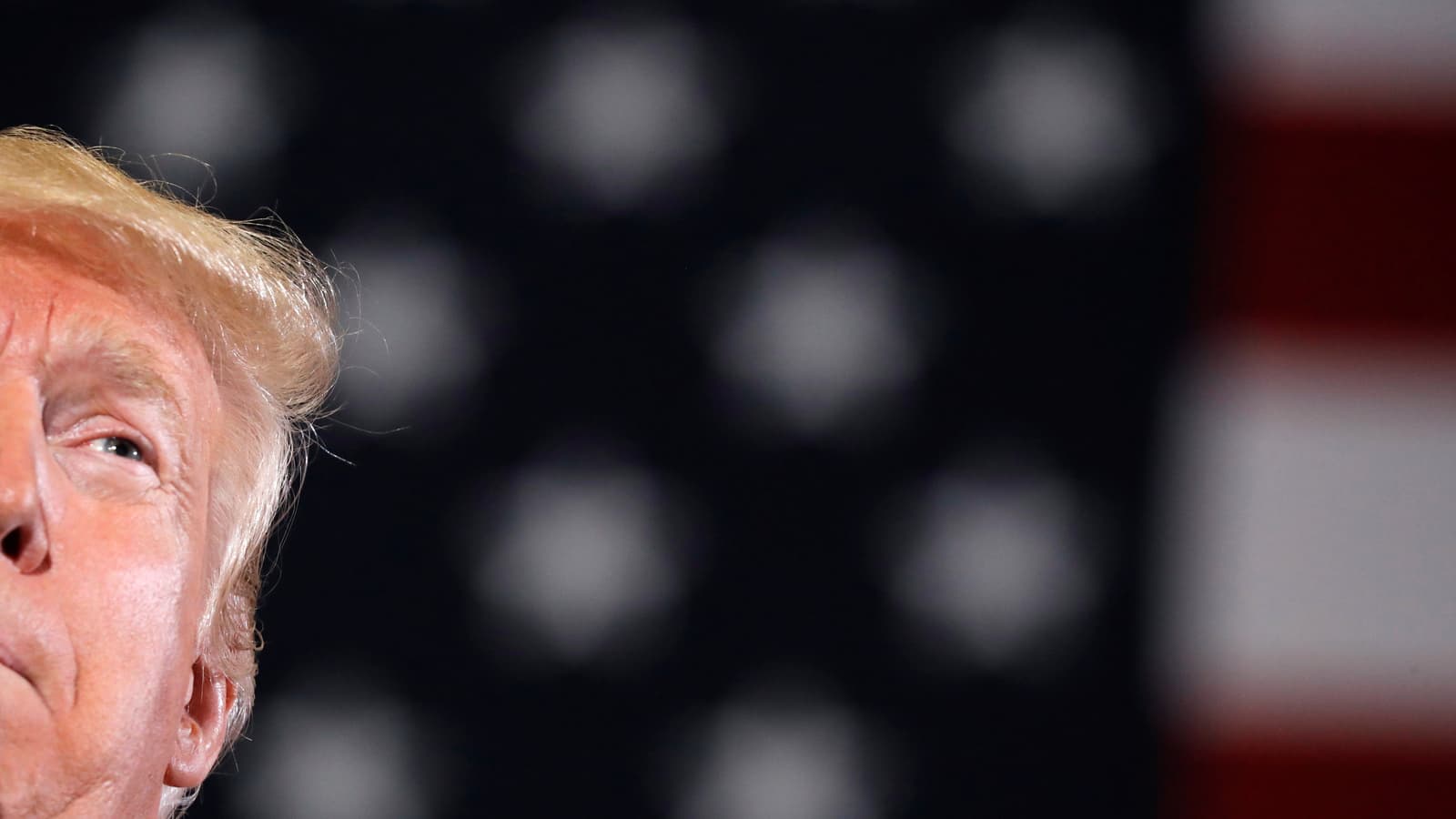 Image of half of Trump's face with blurry US flag in background.