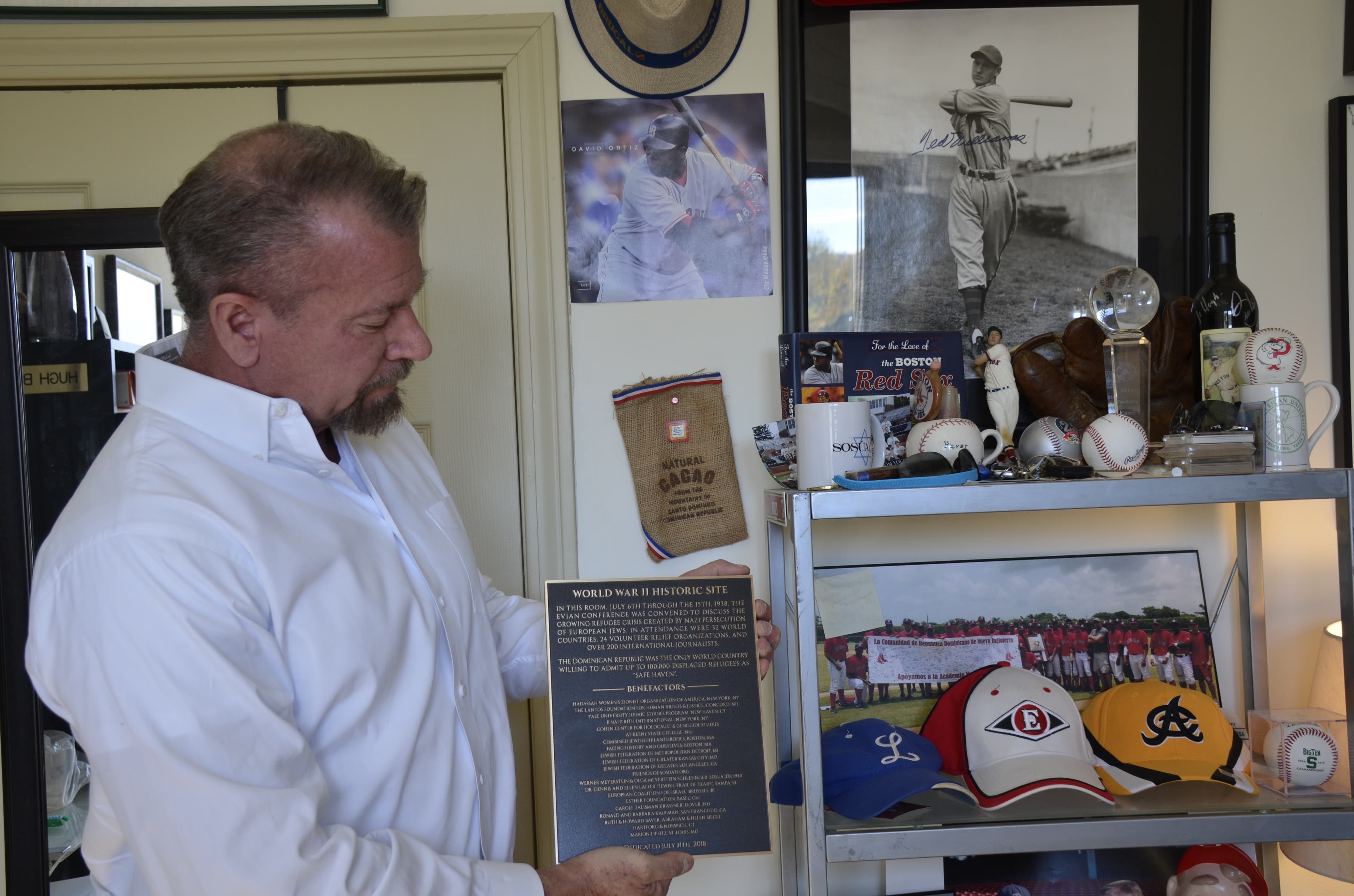 Hugh Baver, in his office in Dover, NH, holds the plaque that will hang at the Hotel Royal in France where the Evian Conference took place in 1938.