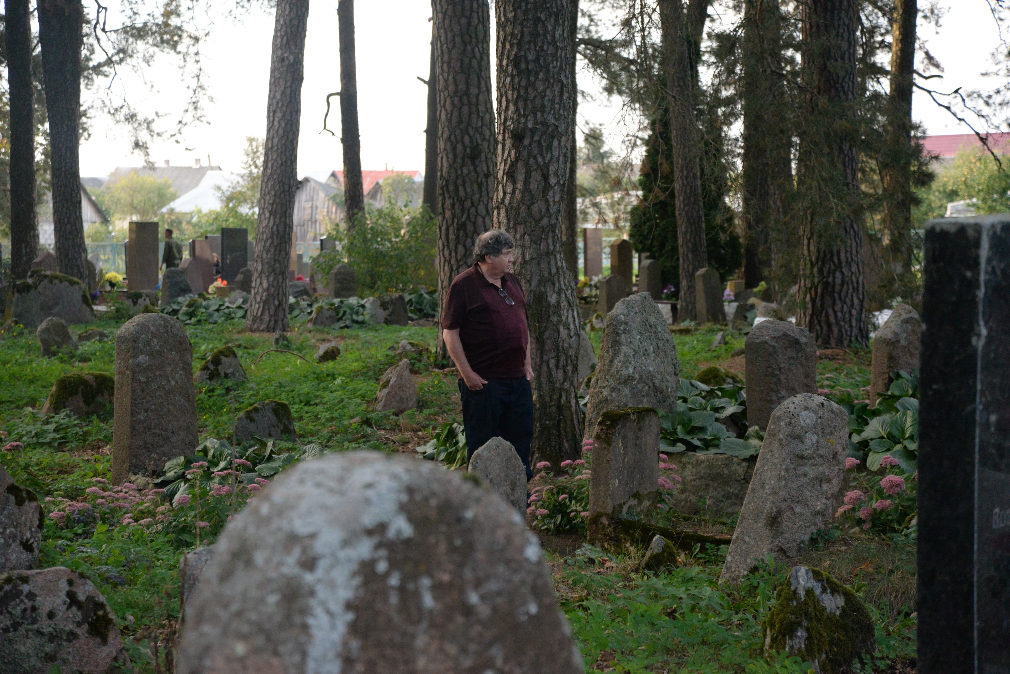 Man standing in lush cemetery