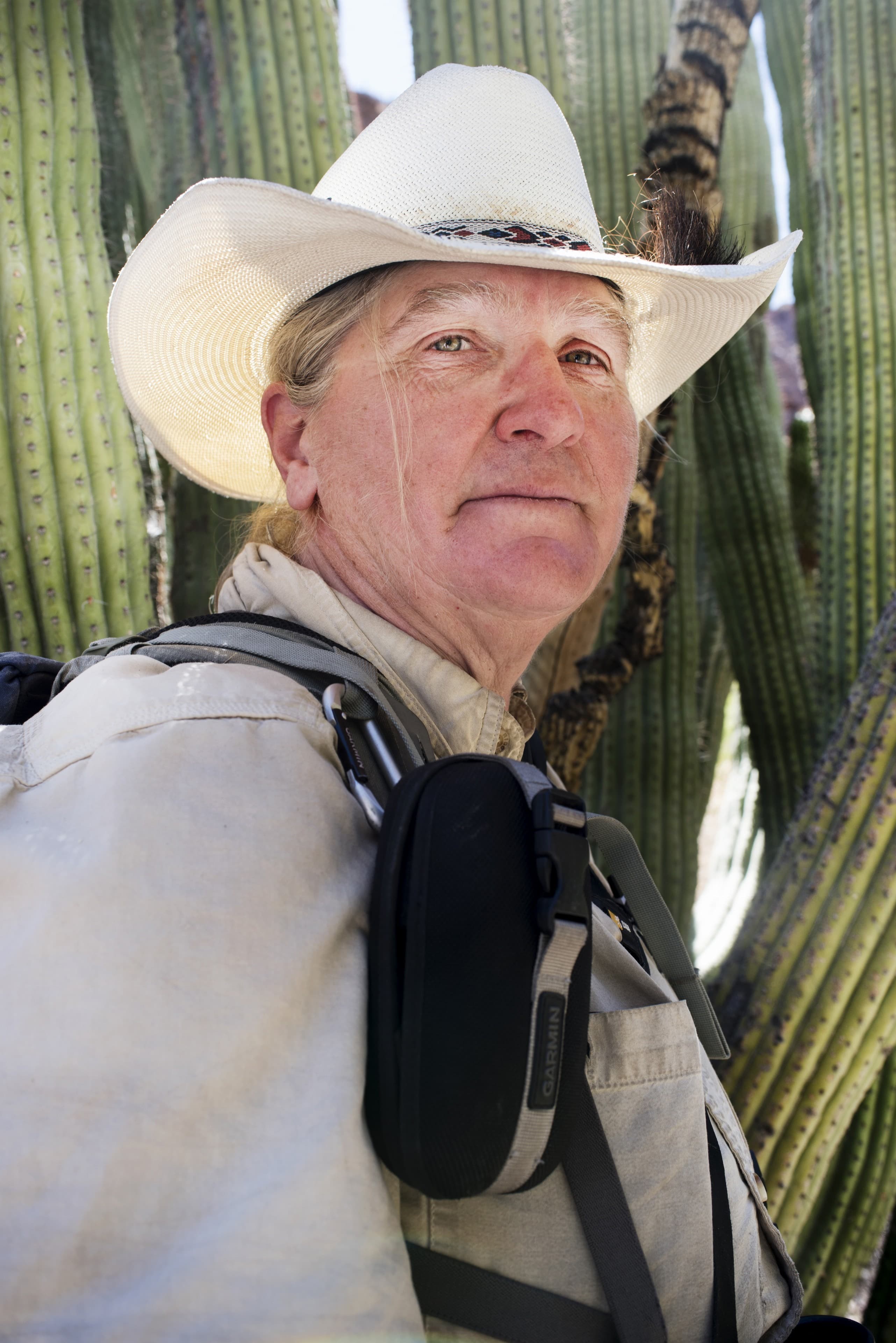 Portrait of woman standing outdoors with technical gear, in hat, weather-worn