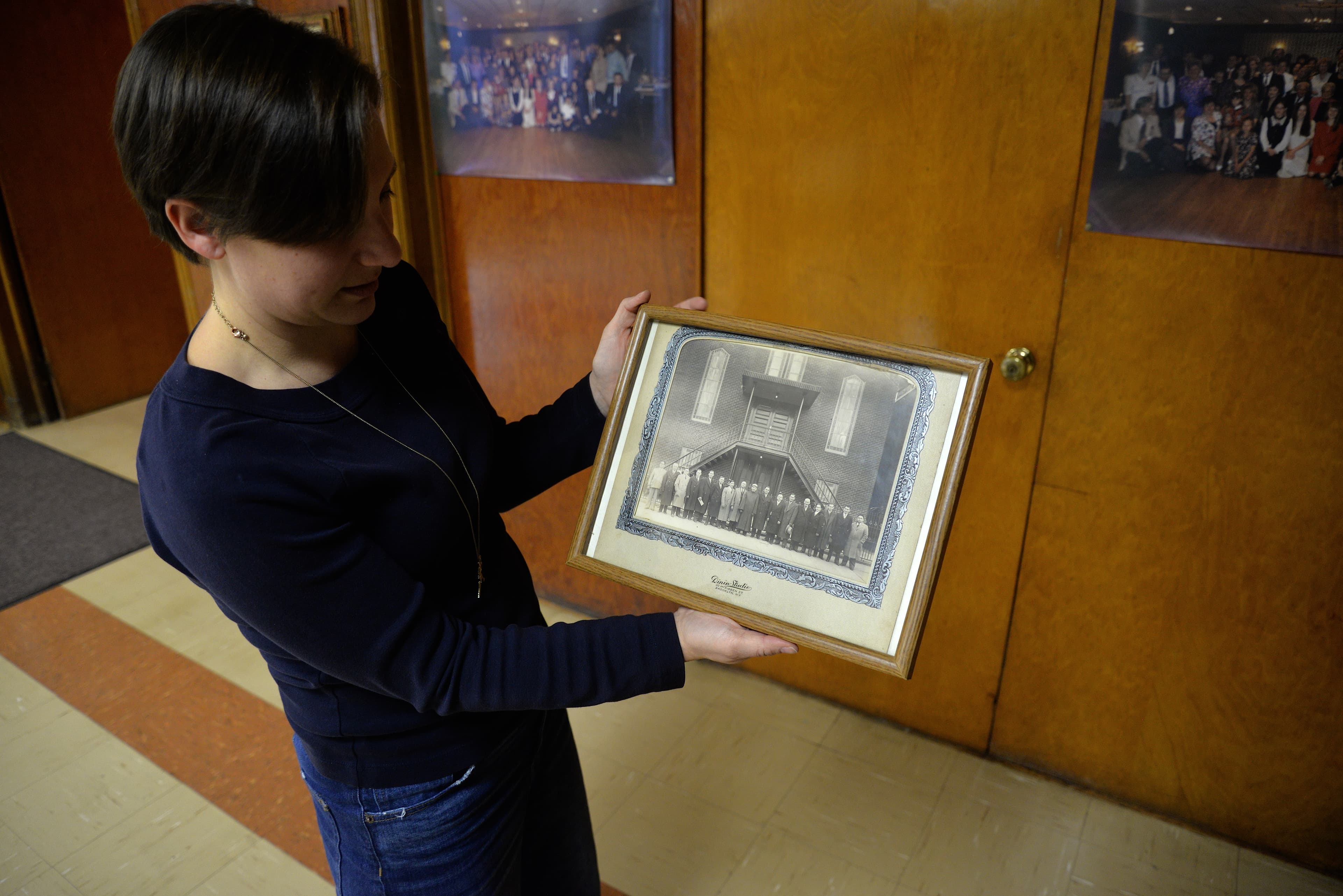 Woman pointing to black and white photo of people in front of building