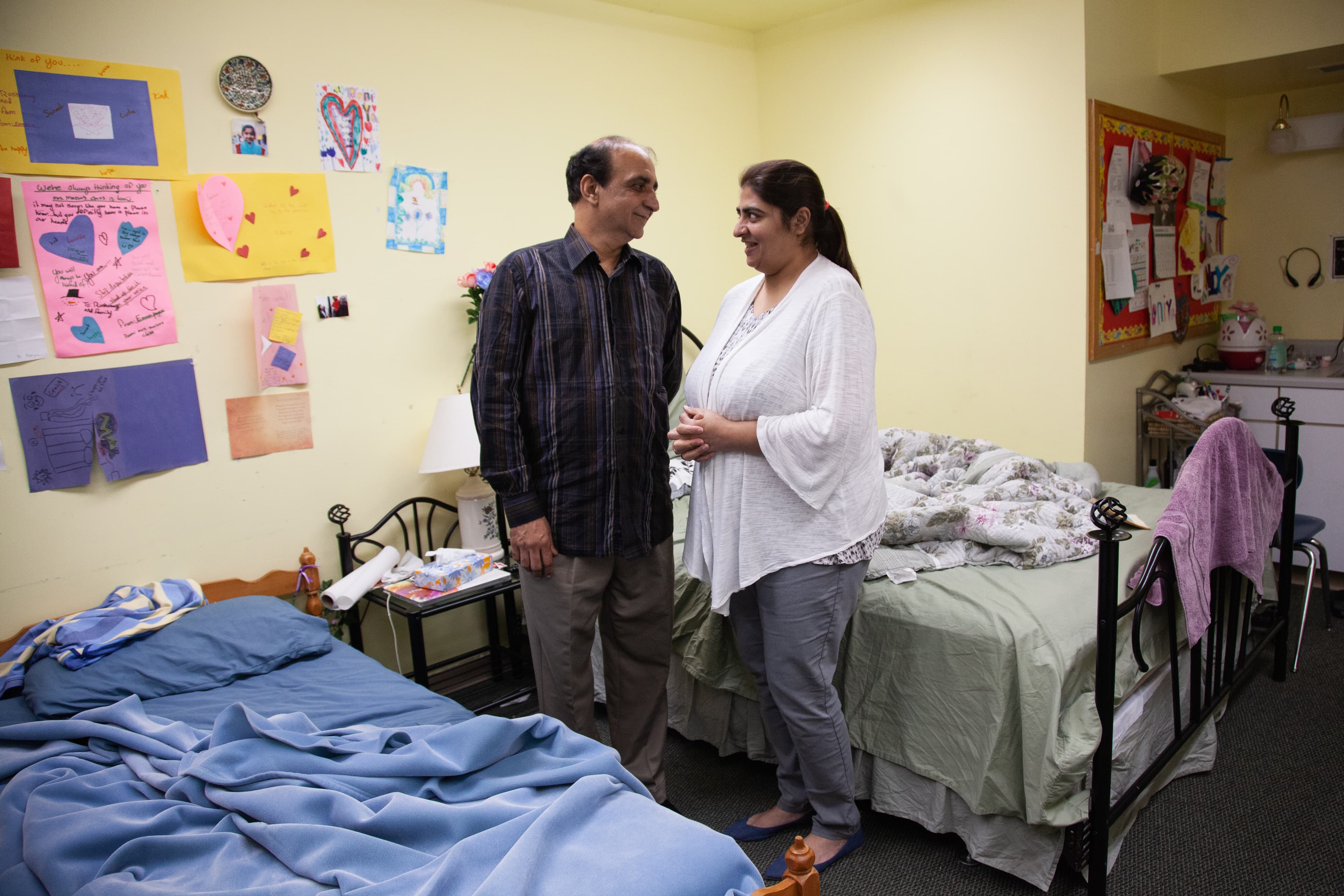 Man and woman stand next to two twin sized bed