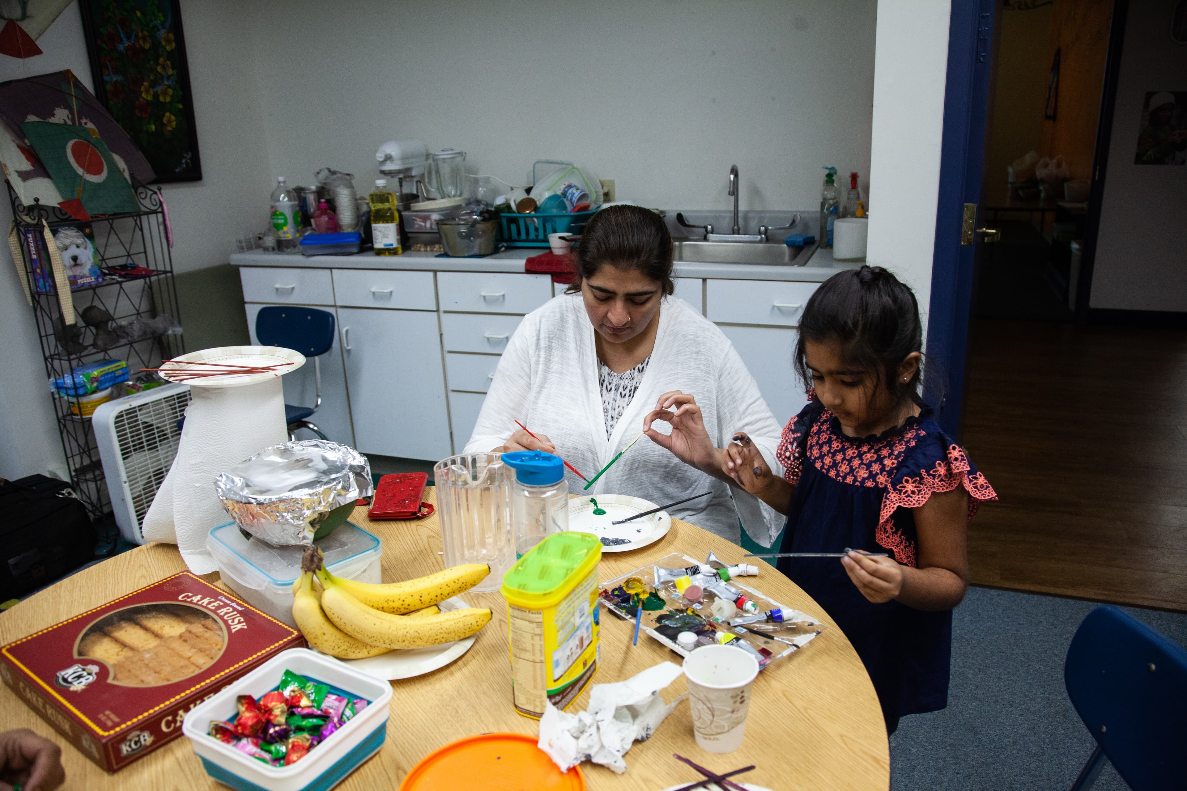 woman and child sit at round table doing arts and crafts