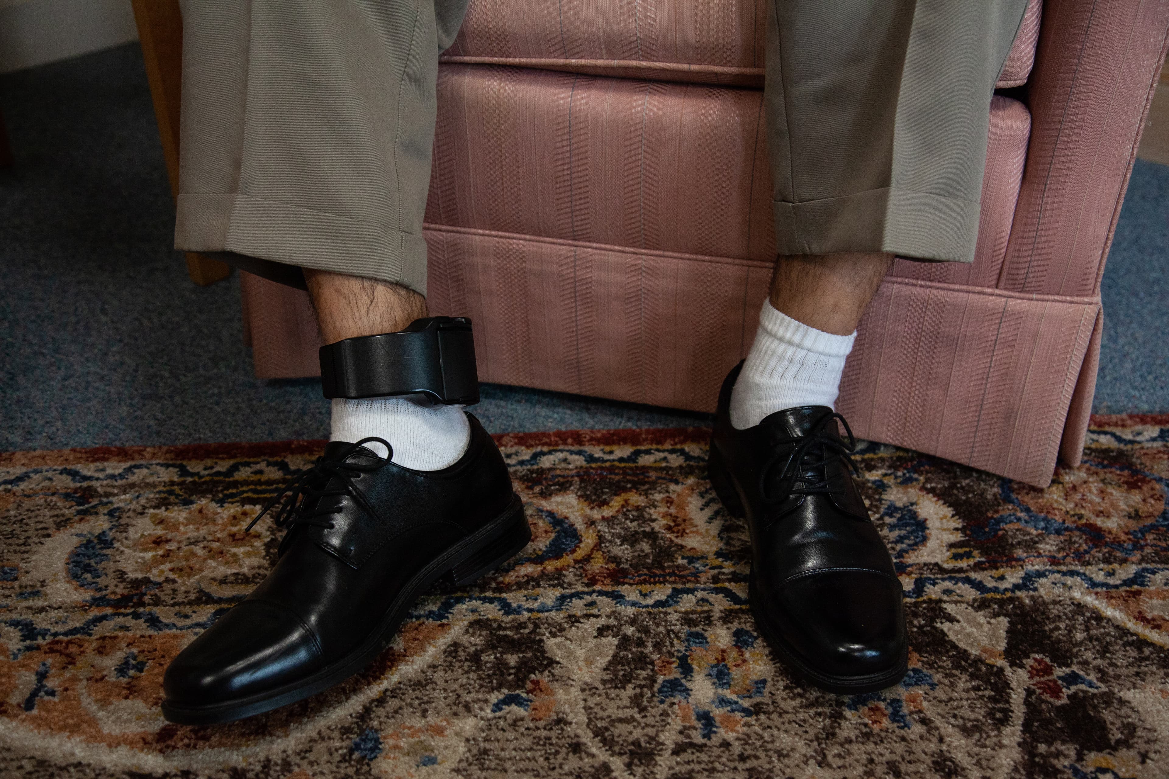 a close-up of man's leg, with ankle monitor strapped around it