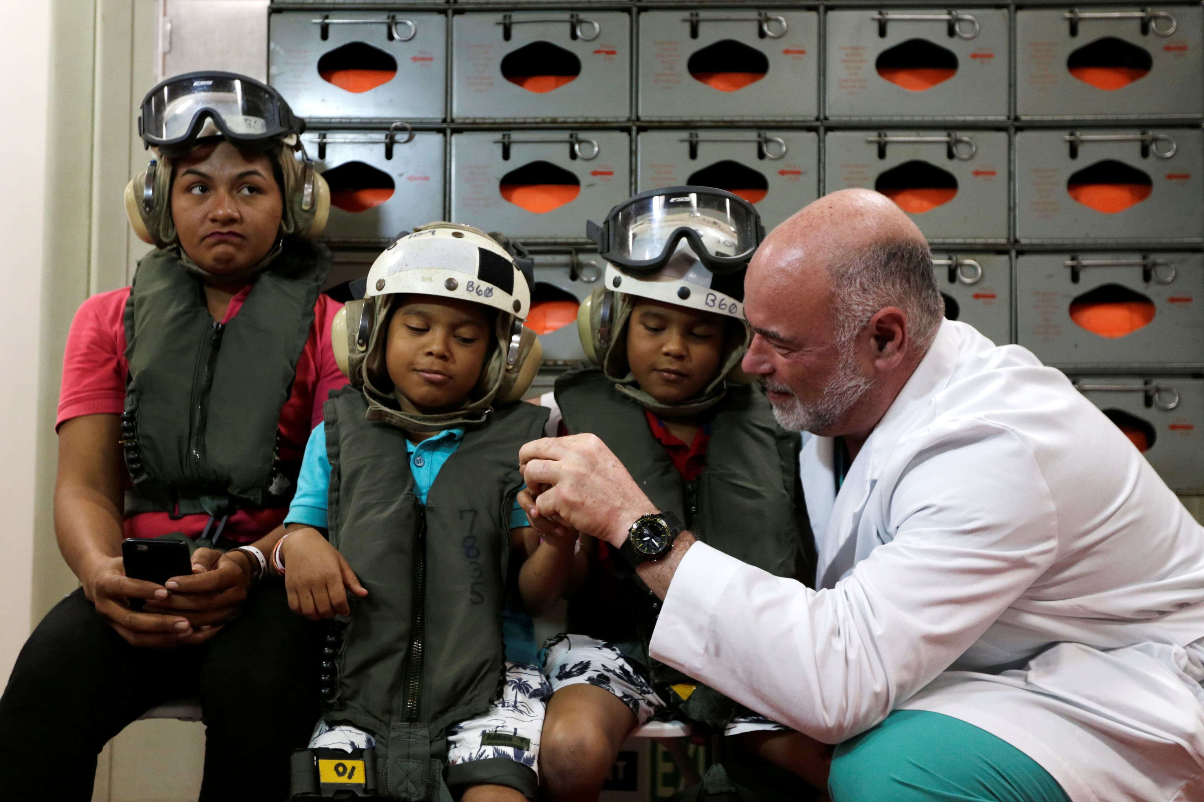 A member of the crew of the hospital ship USNS Comfort plays with two children