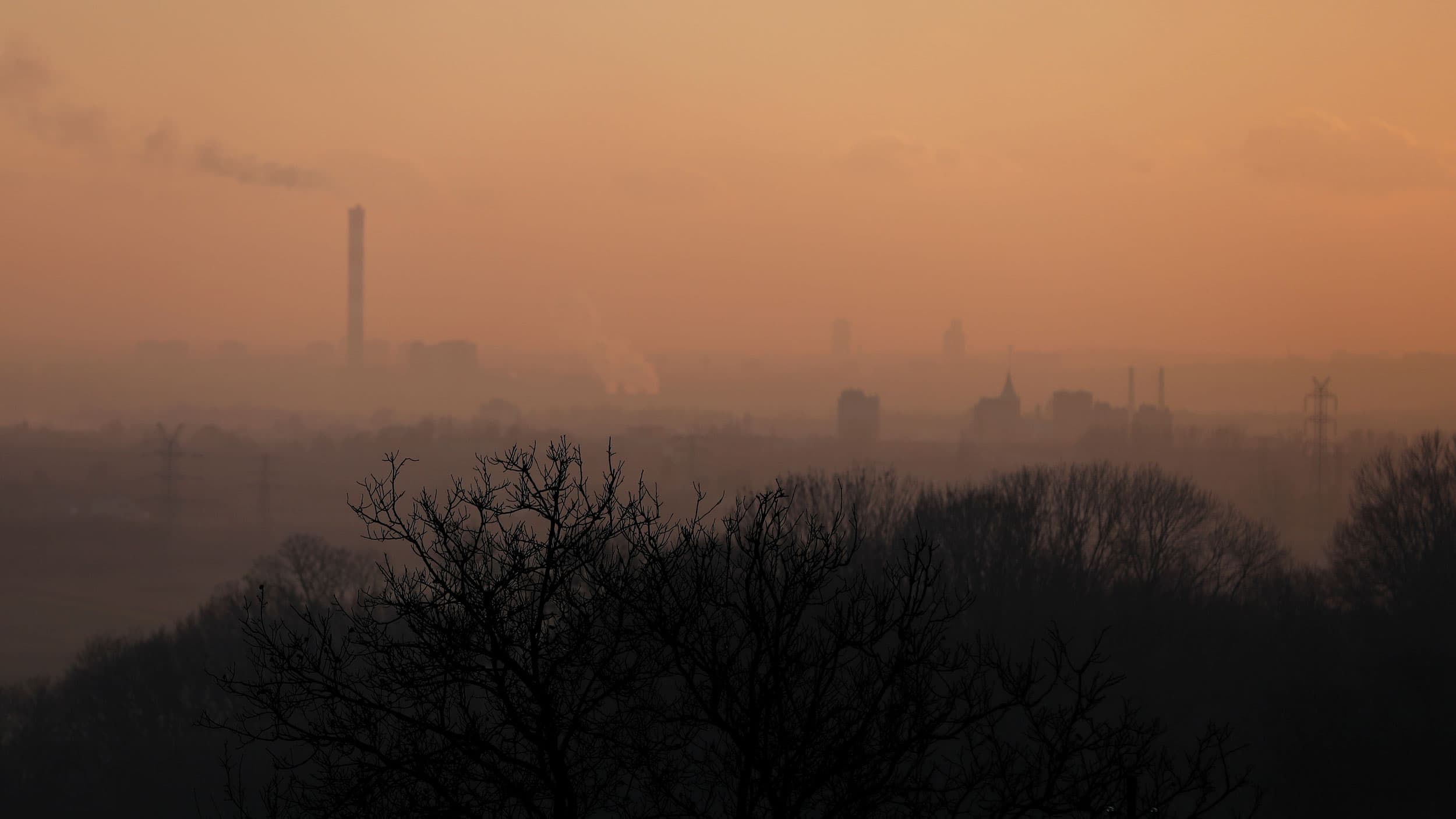 The tops of buildings are barely visible through a thick layer of smog.