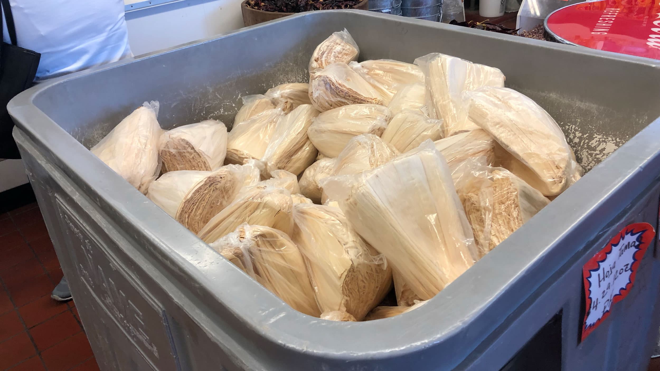 Corn husks are bundled in plastic bags for sale at the market.
