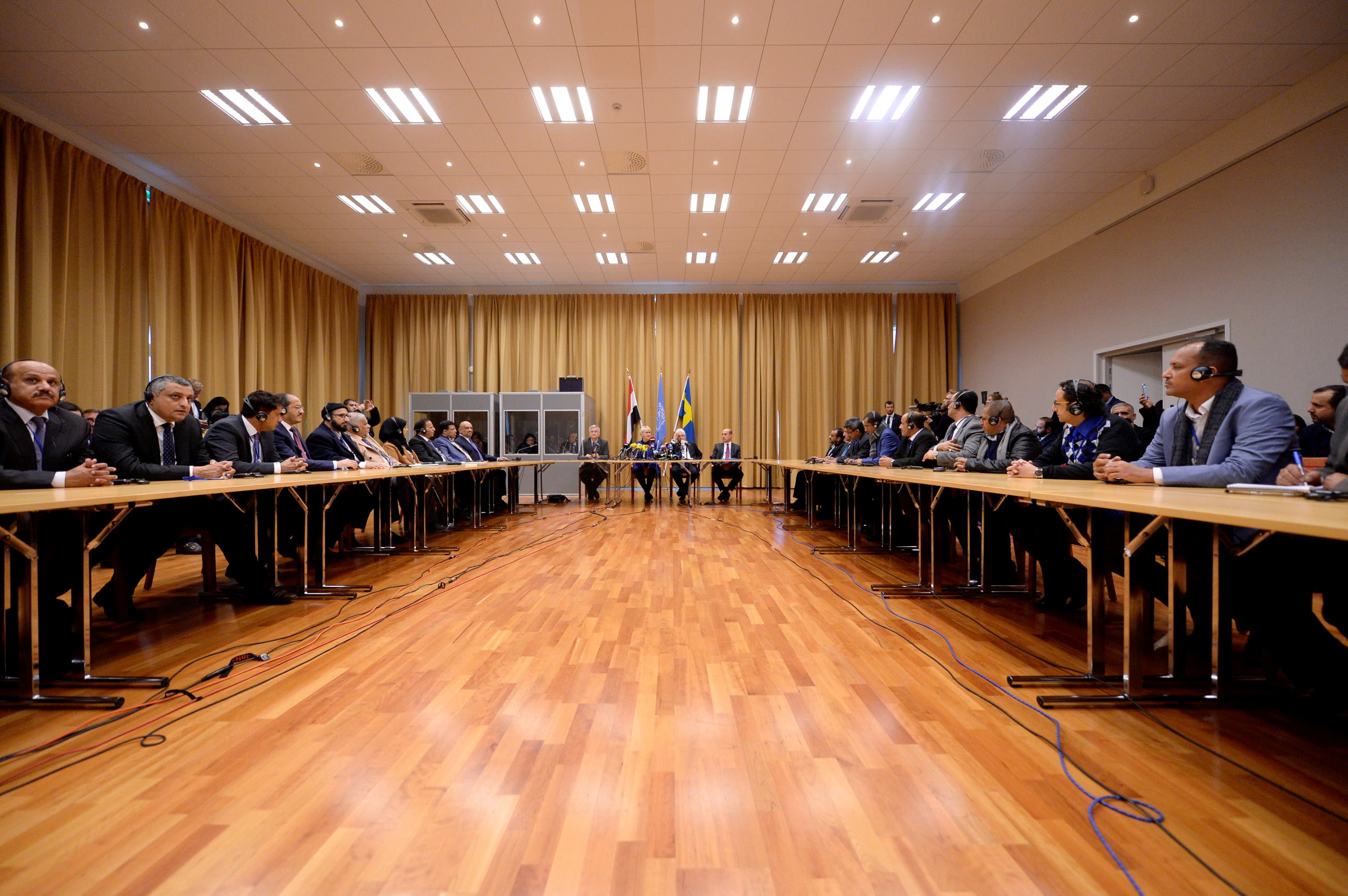 delegates sit across each other in a large room with a wood floor