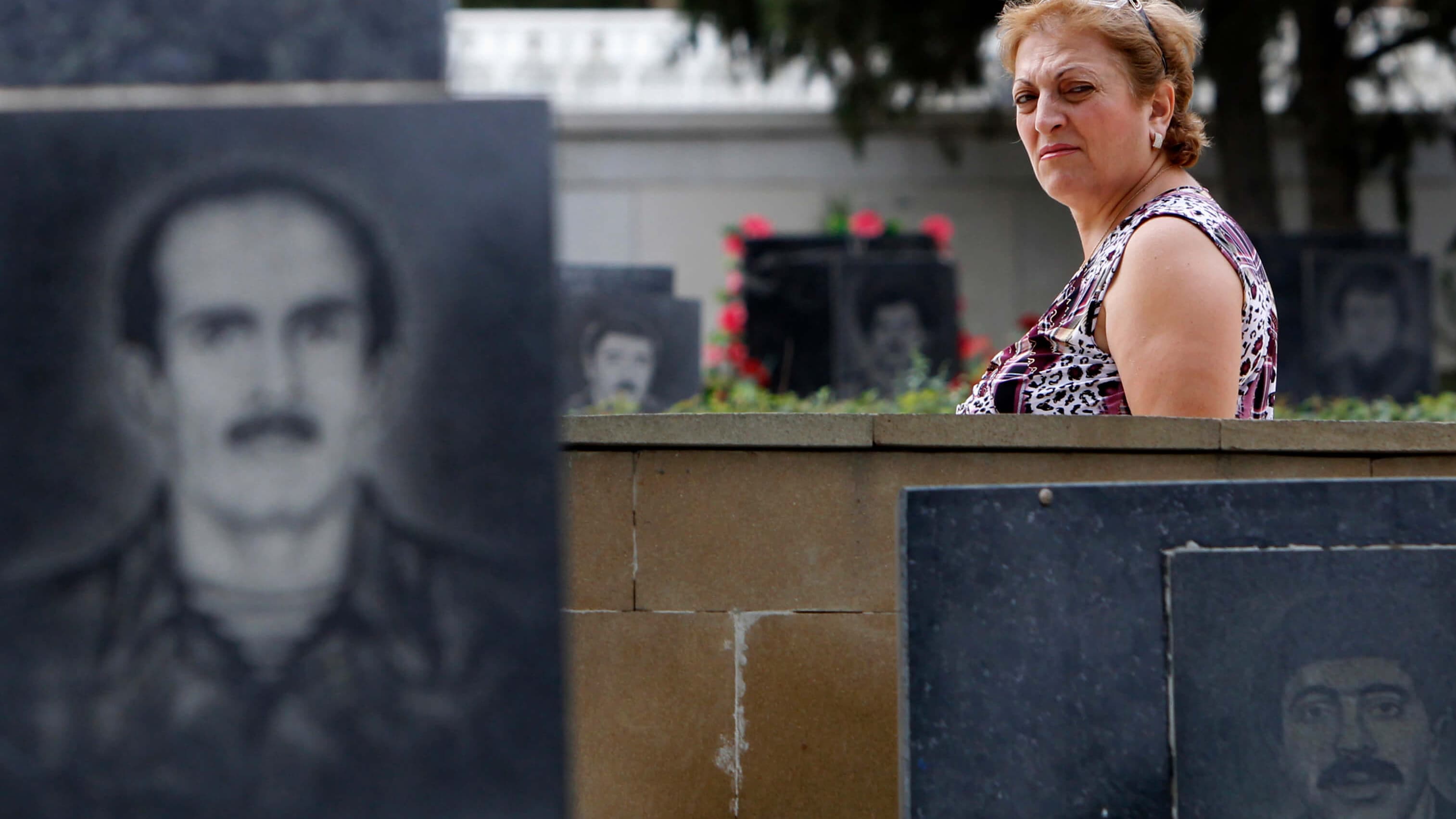 A woman walks past tombstones in the Alley of Martyrs memorial cemetery in Baku, Azerbaijan, Sept. 8, 2012.