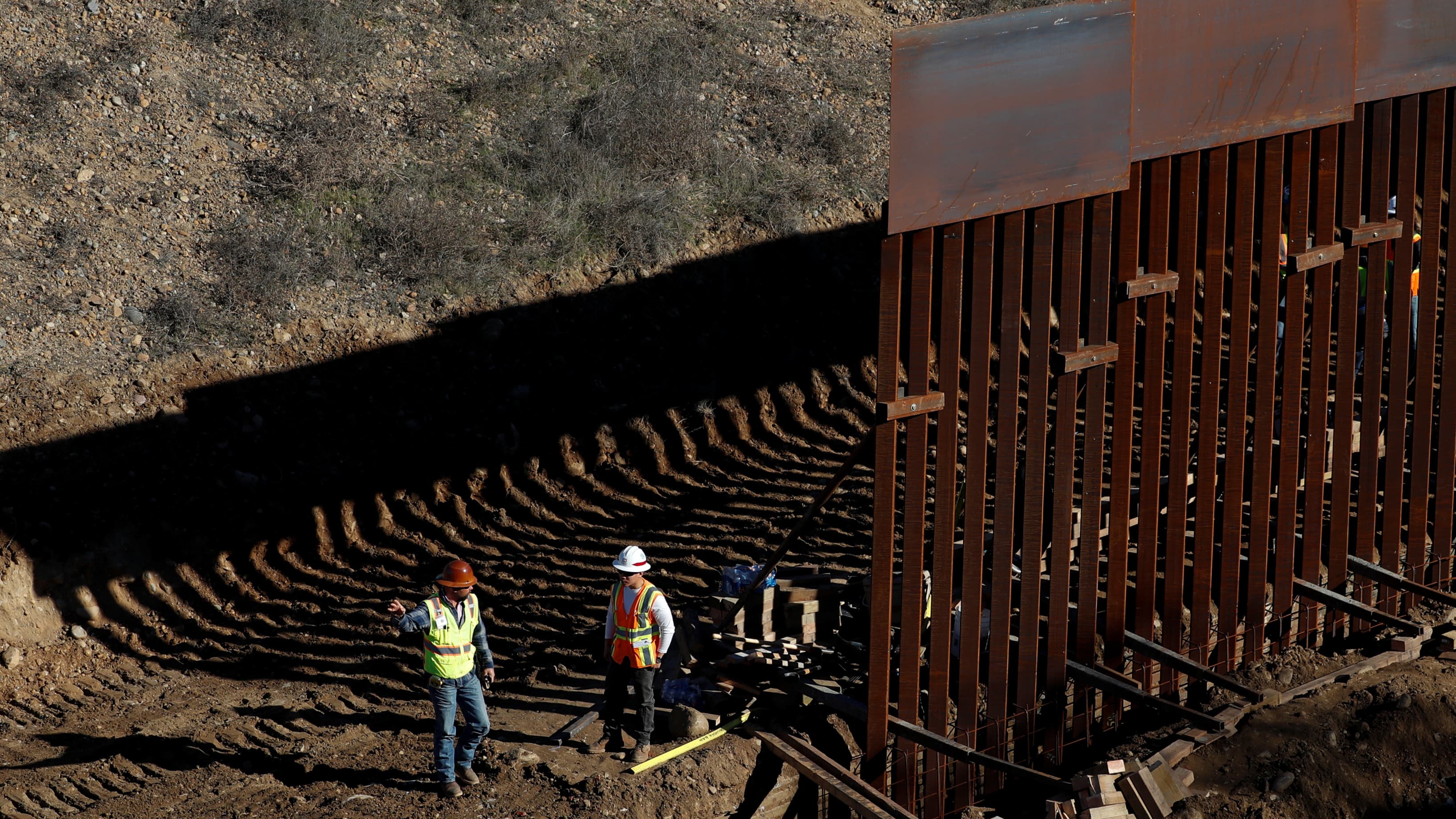 Workers construct border wall.