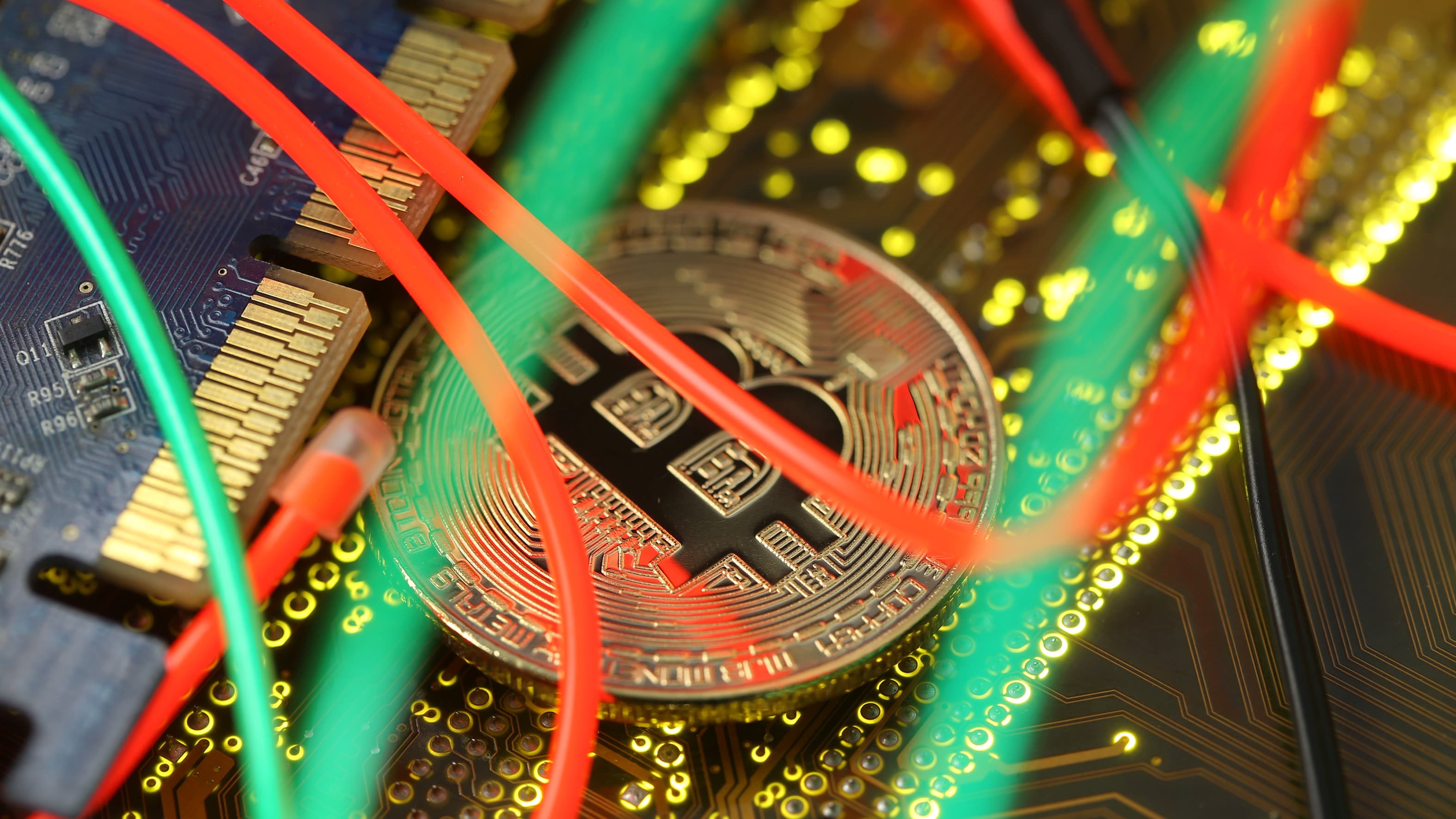 A gold coin with the letter B stamped amidst green and red wires.