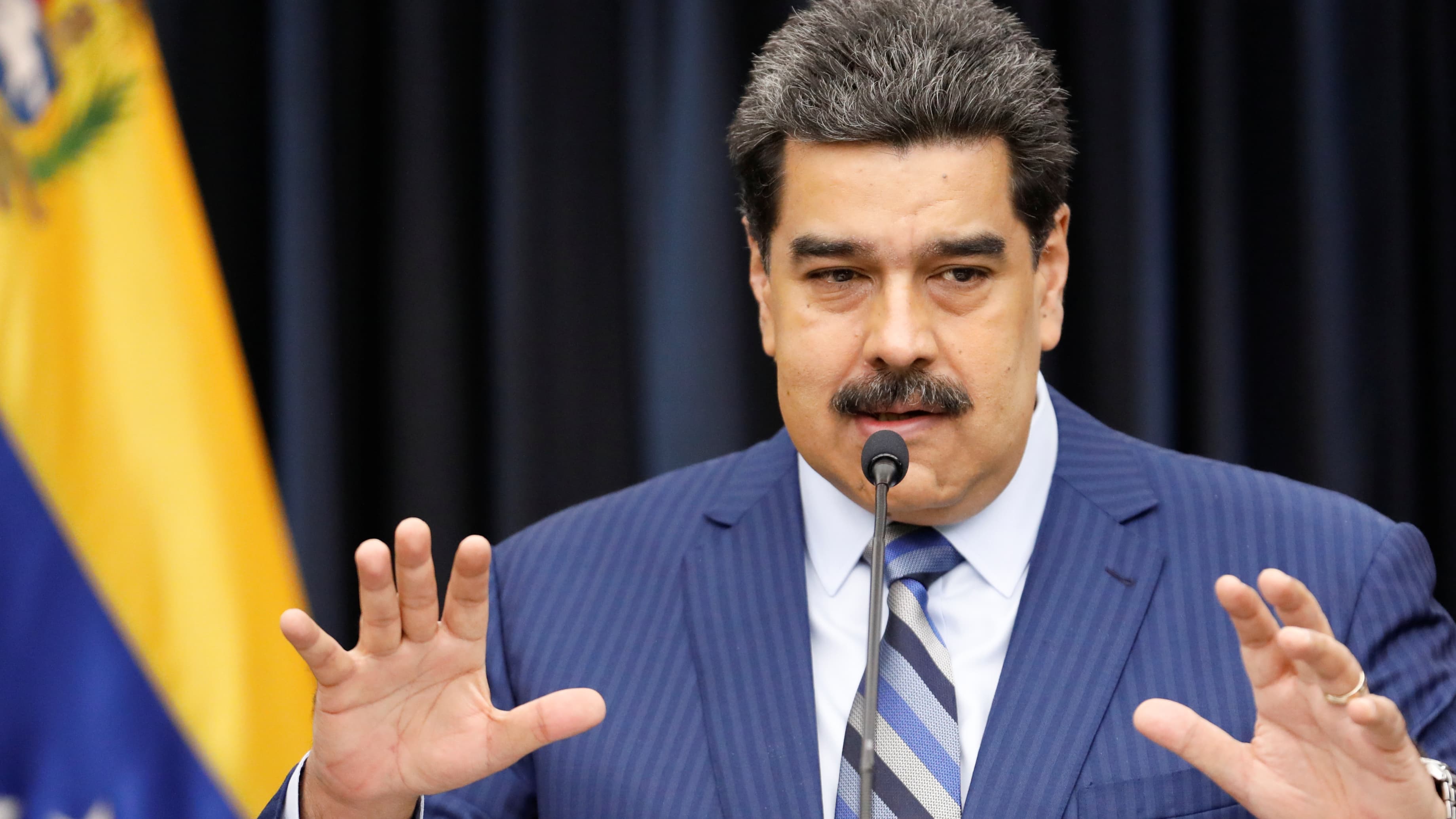 Venezuela President Maduro in blue suit holds his hands out and speaks at news conference.