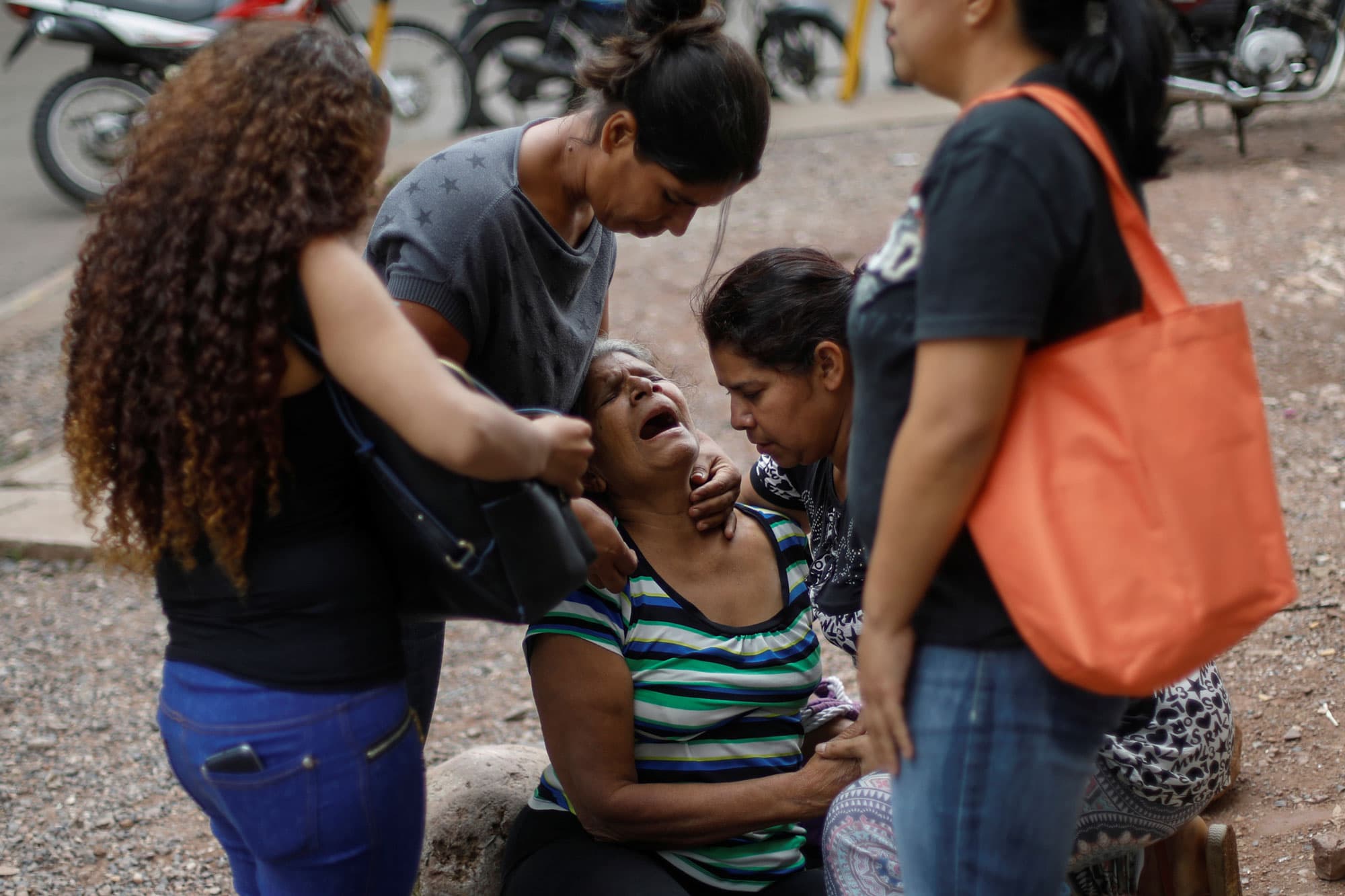 A woman is shown weeping surrounded by four other women near the coffin.