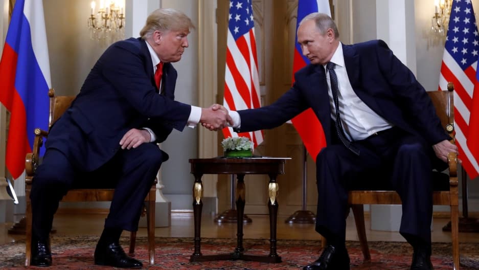 Trump and Putin shake hands.