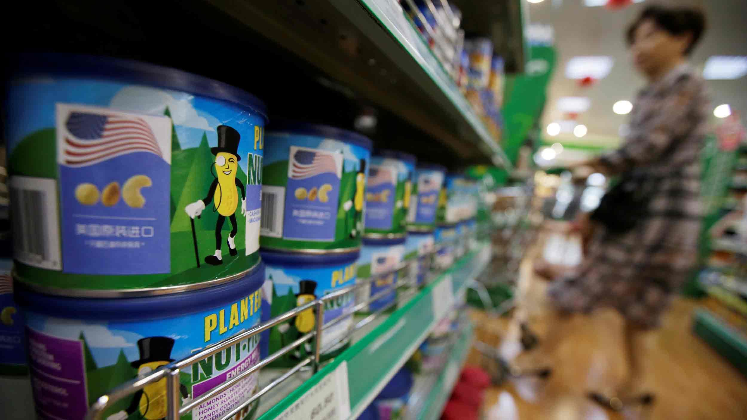 Cans of nuts are lined up on a supermarket shelf