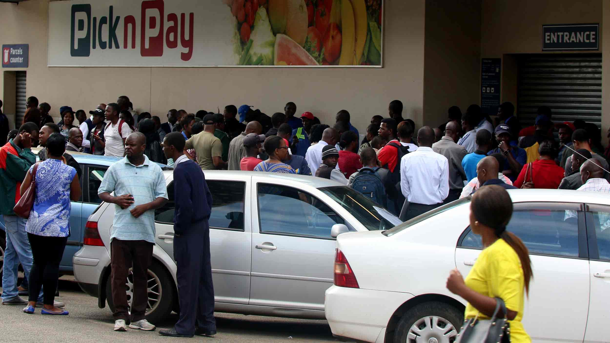 A crowd of people stand outside a closed supermarket