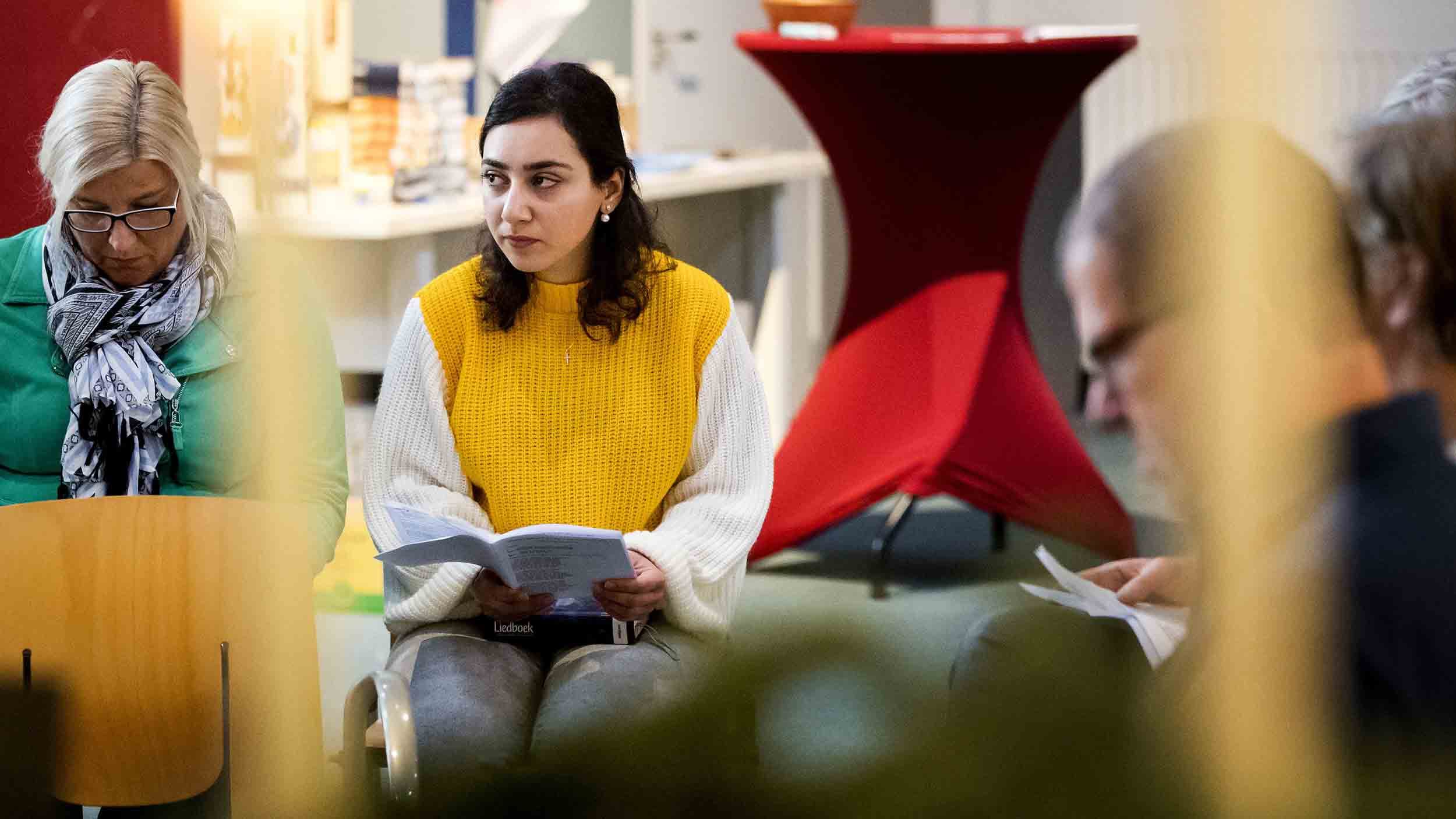 A girl in yellow sits during a church service
