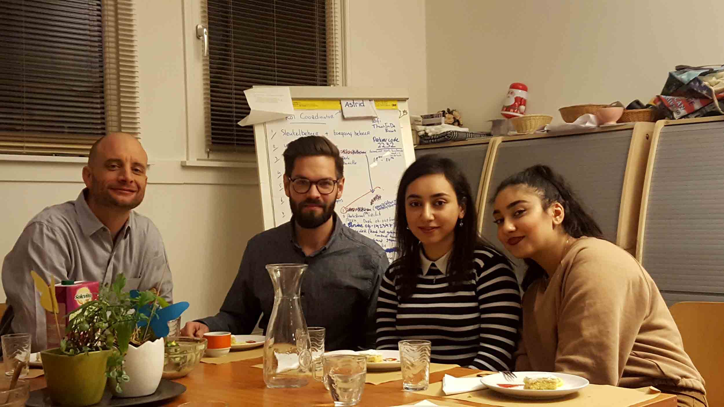 Four people pose for a photograph at a dinner table.