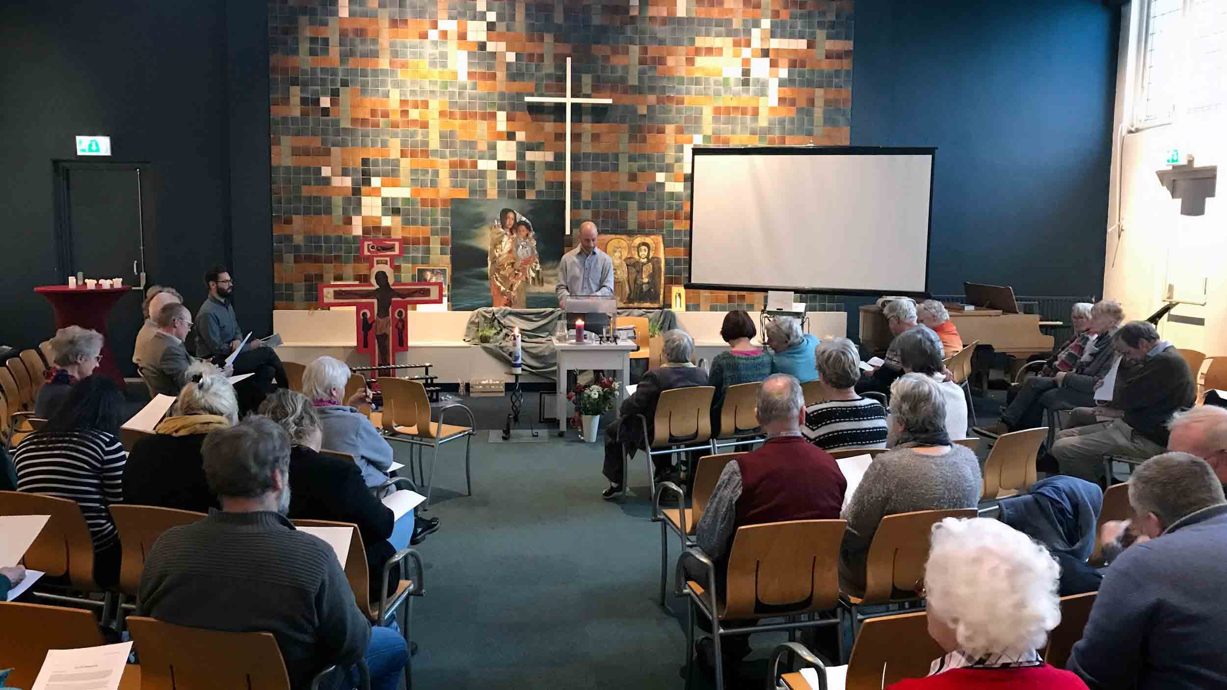 A preacher stands at the front of a mostly full church