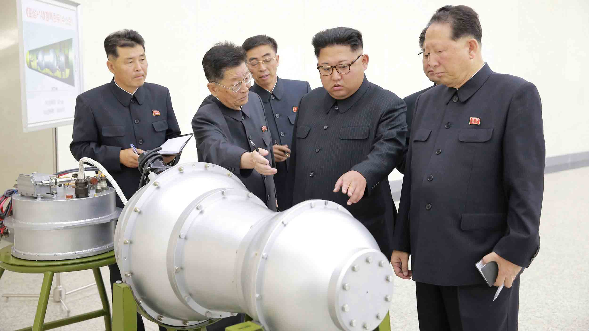 Kim Jong-un inspects a large metal piece of equipment with others around him.