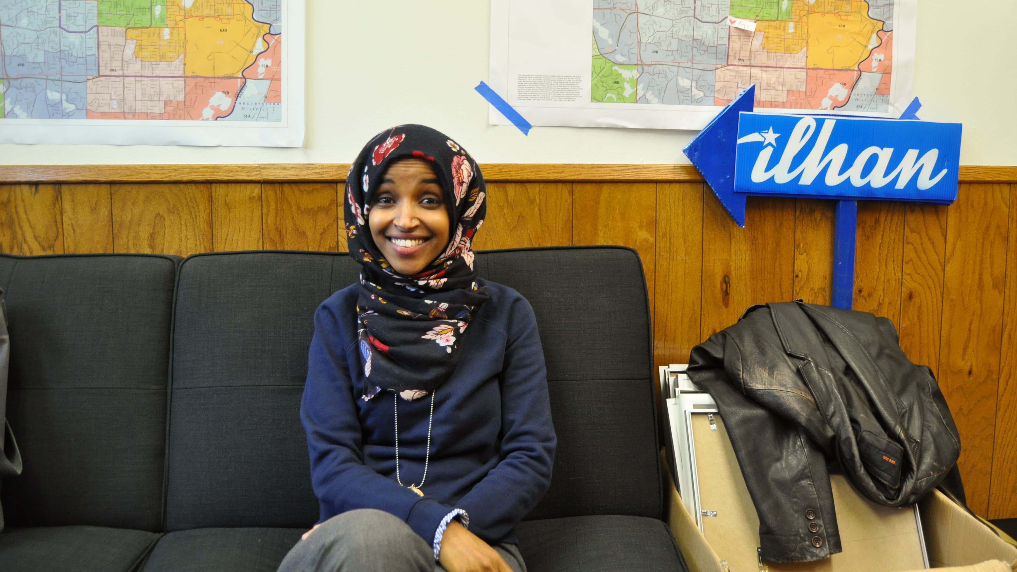 Woman sits on sofa, smiles for camera