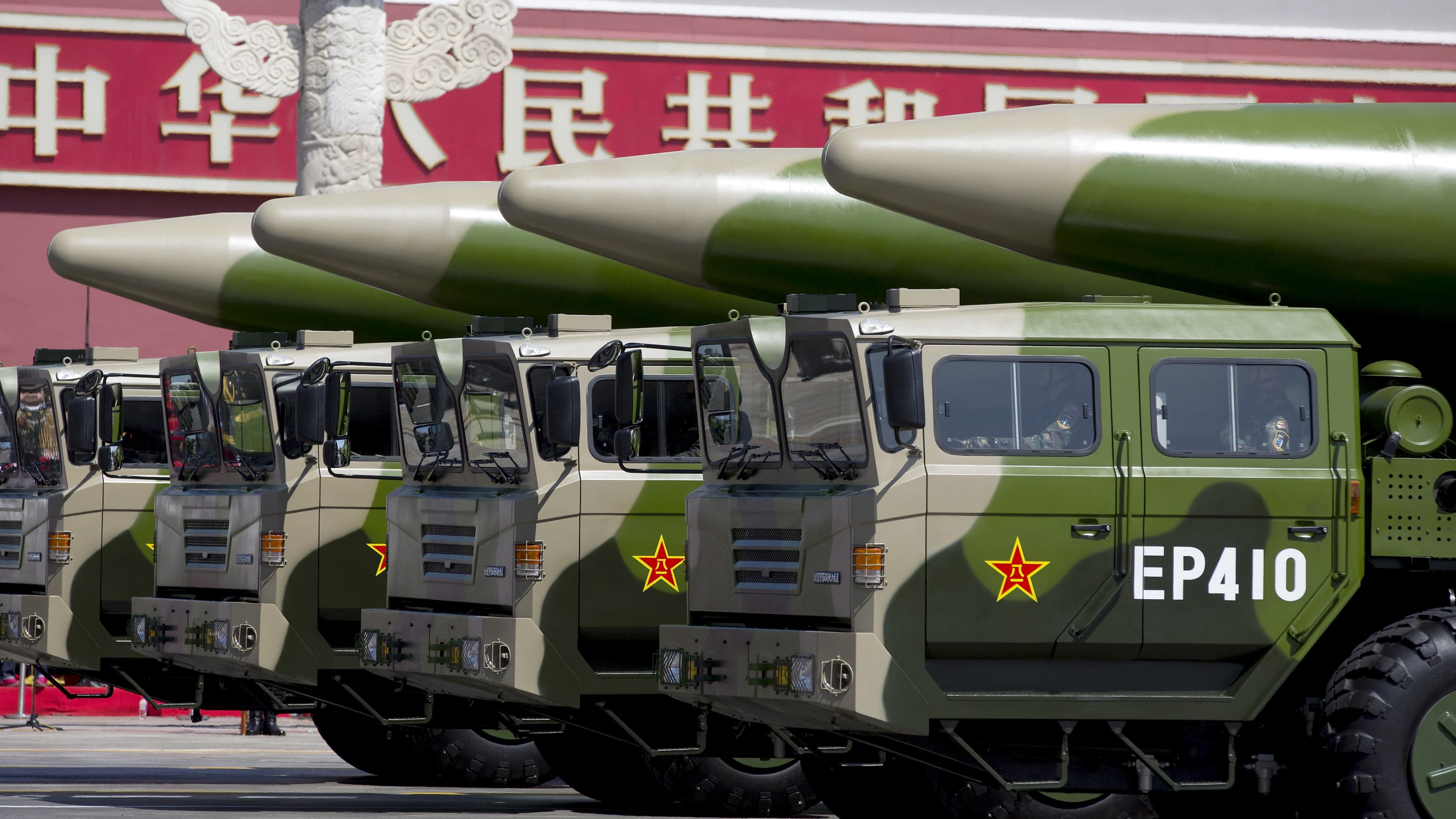 Green-colored military vehicles carry DF-26 ballistic missiles.