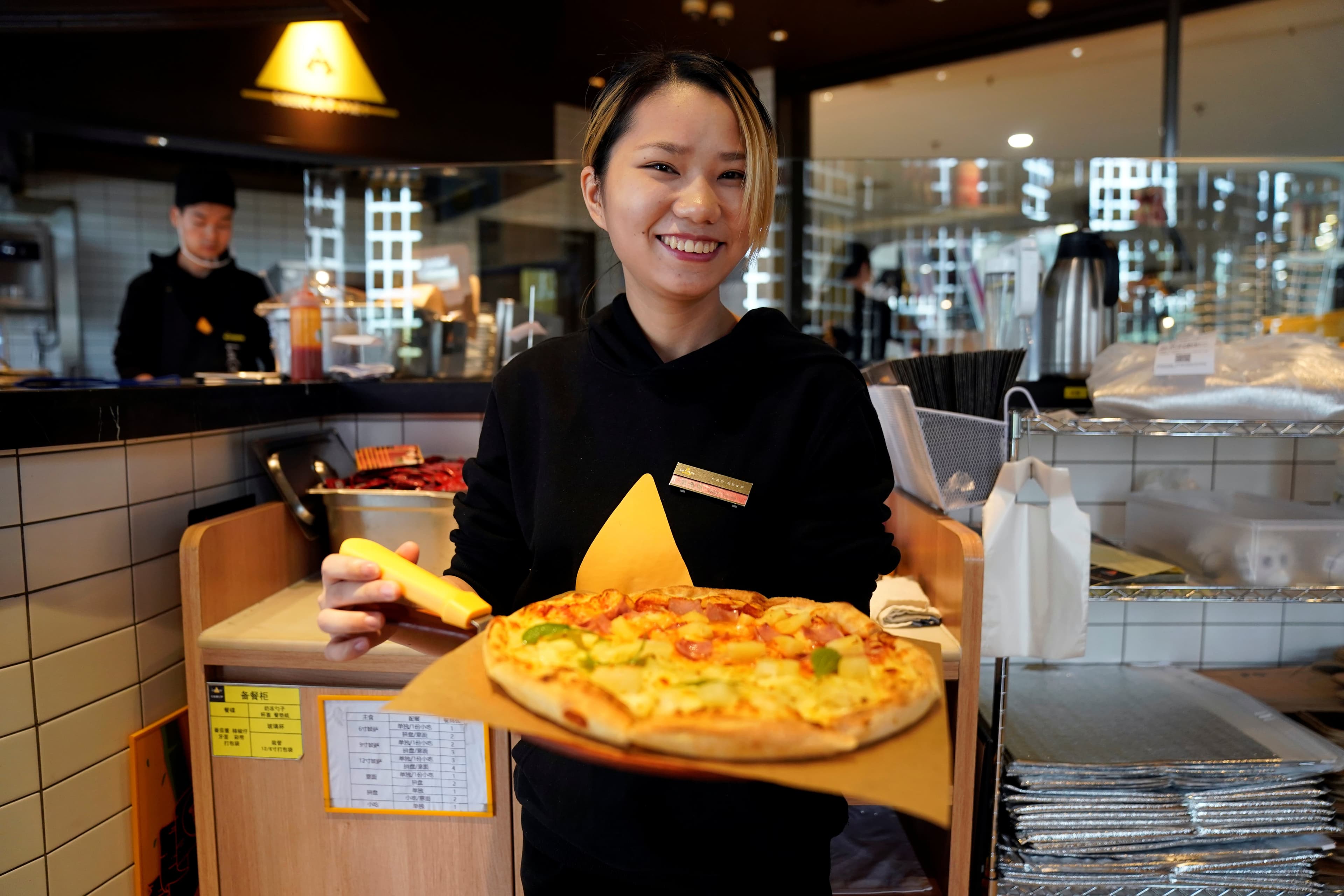 a woman shows a pizza with durian on it