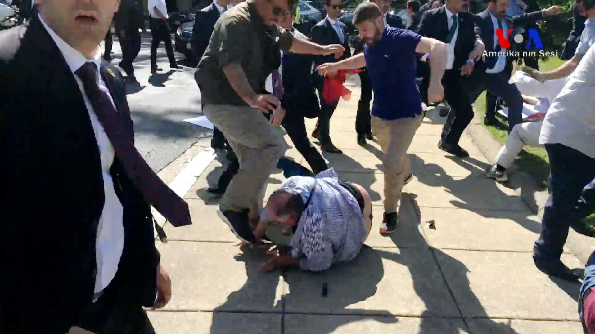 two men kick a protester on the ground