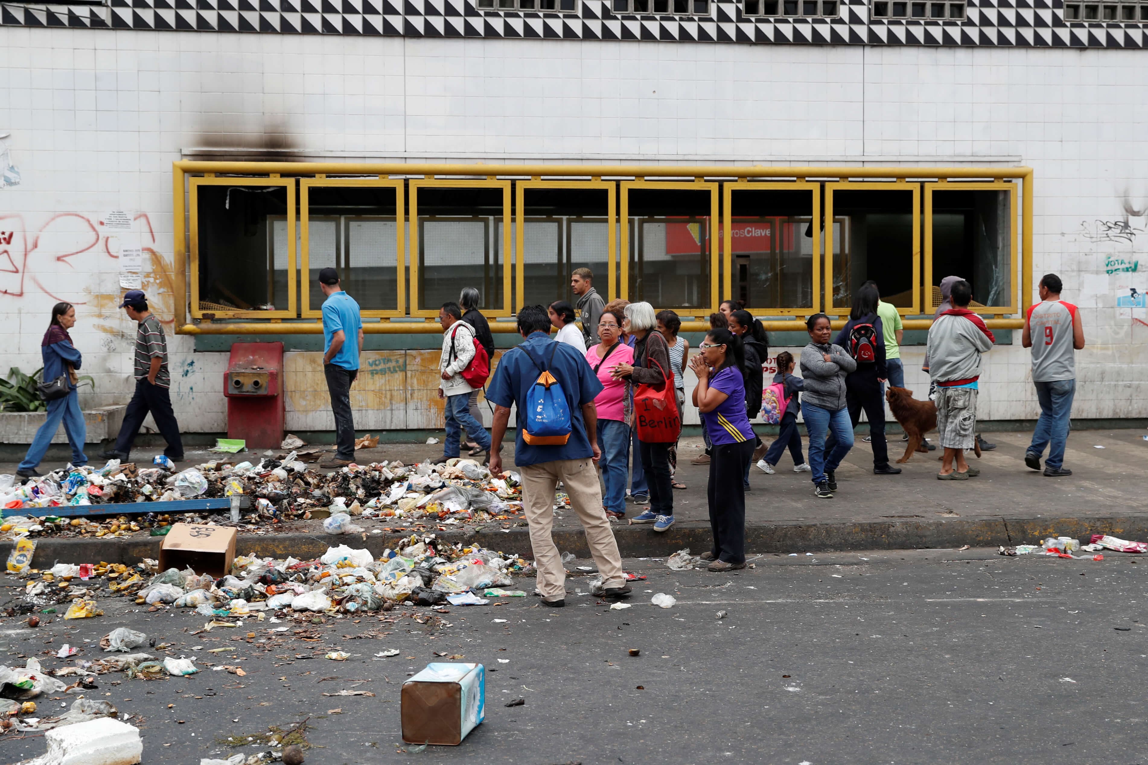 About a dozen people stand outside of a damaged metro station