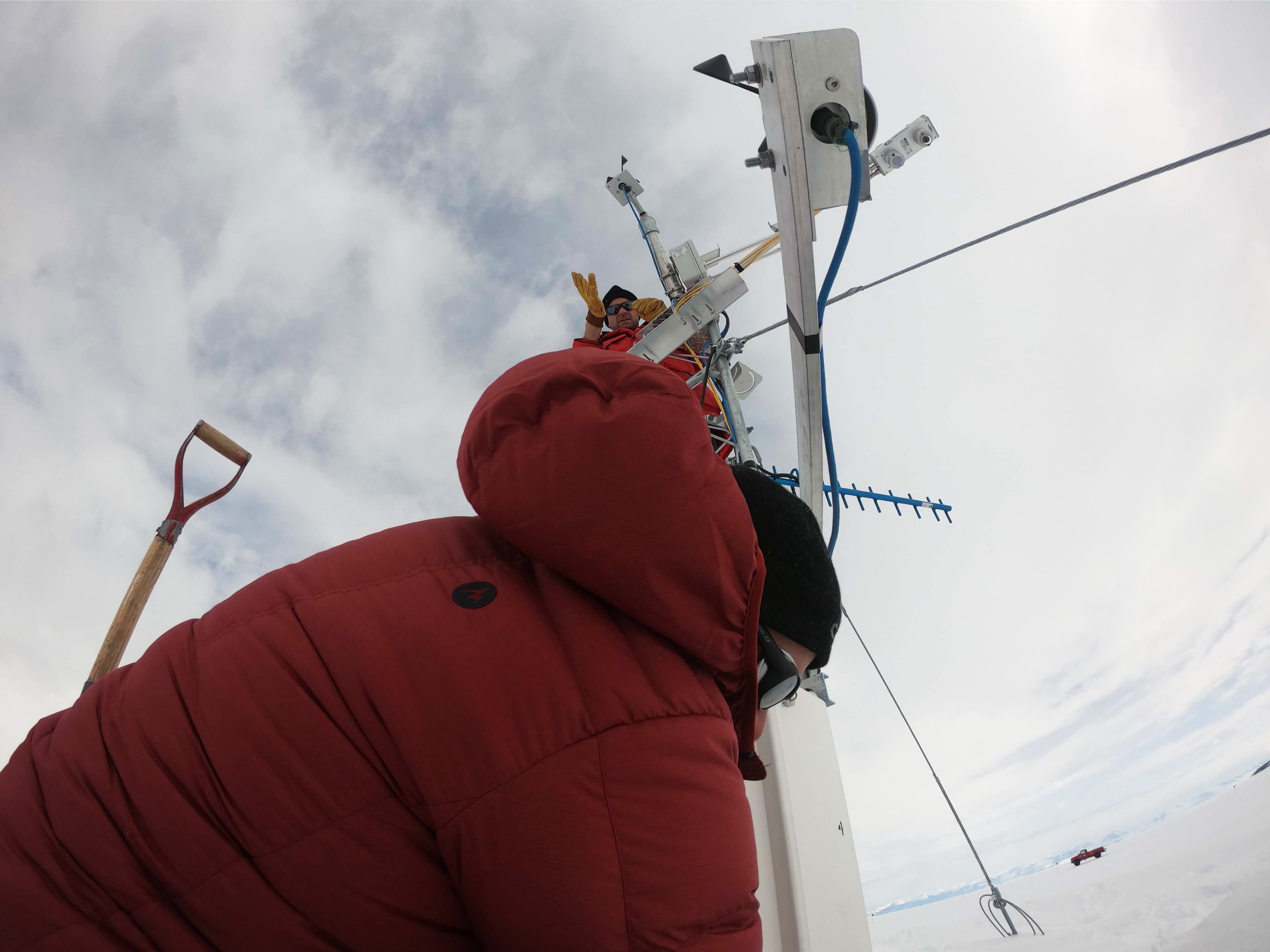 a man in a red coat stands at the bottom of a tall white pole