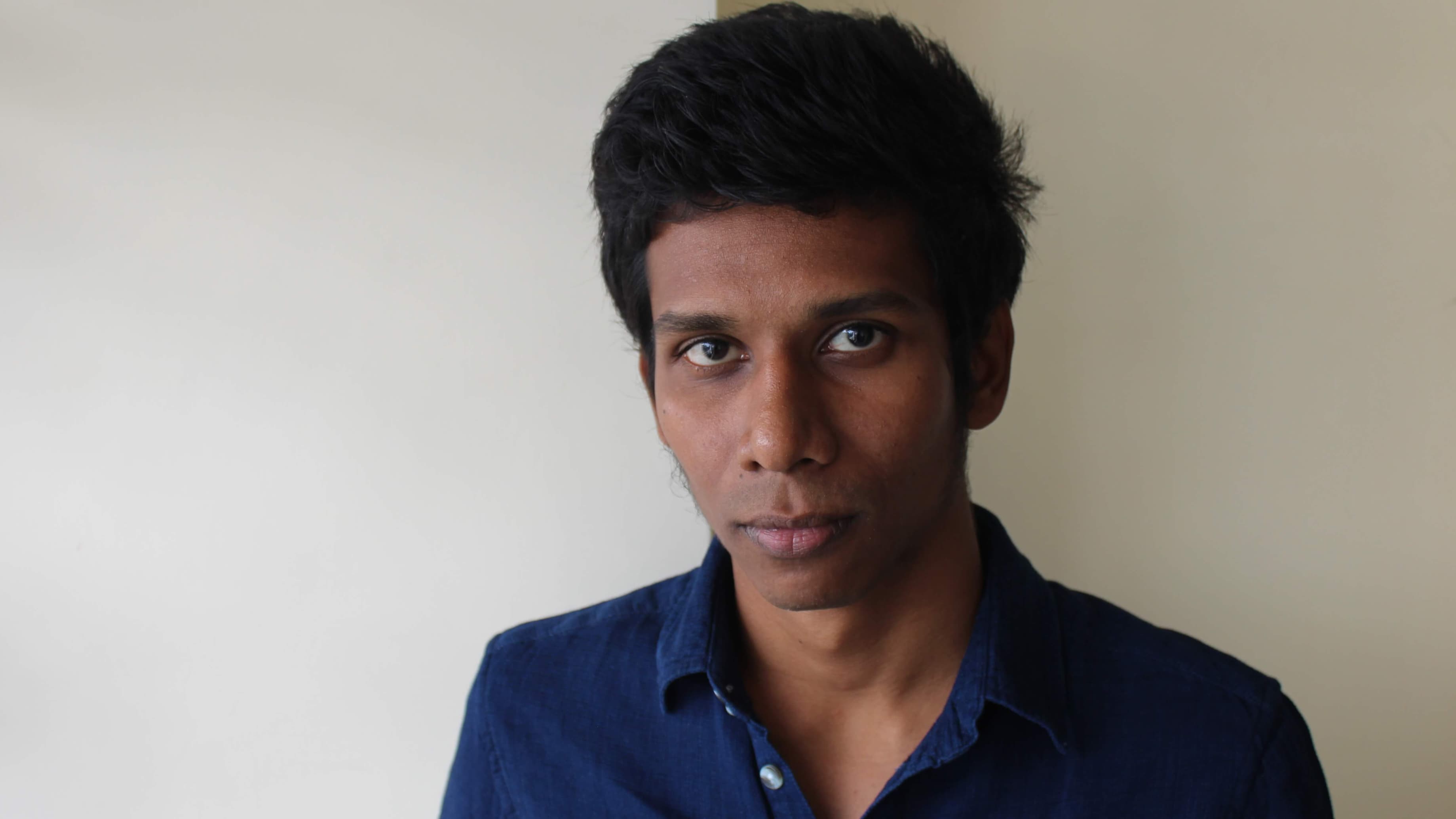 Portrait of a Myanmar poet wearing a blue shirt.