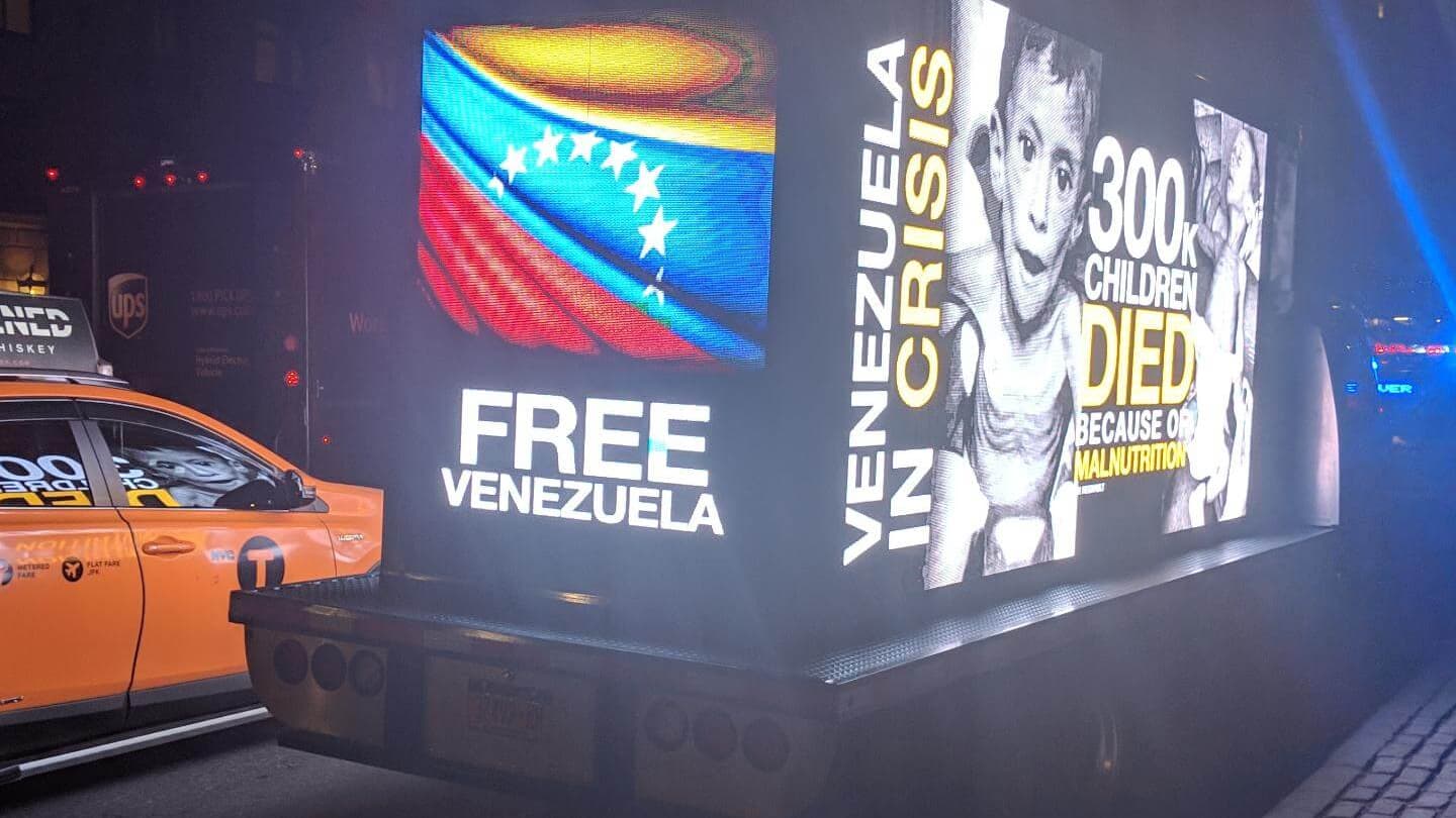 A glowing billboard on a mobile truck says Free Venezuela.