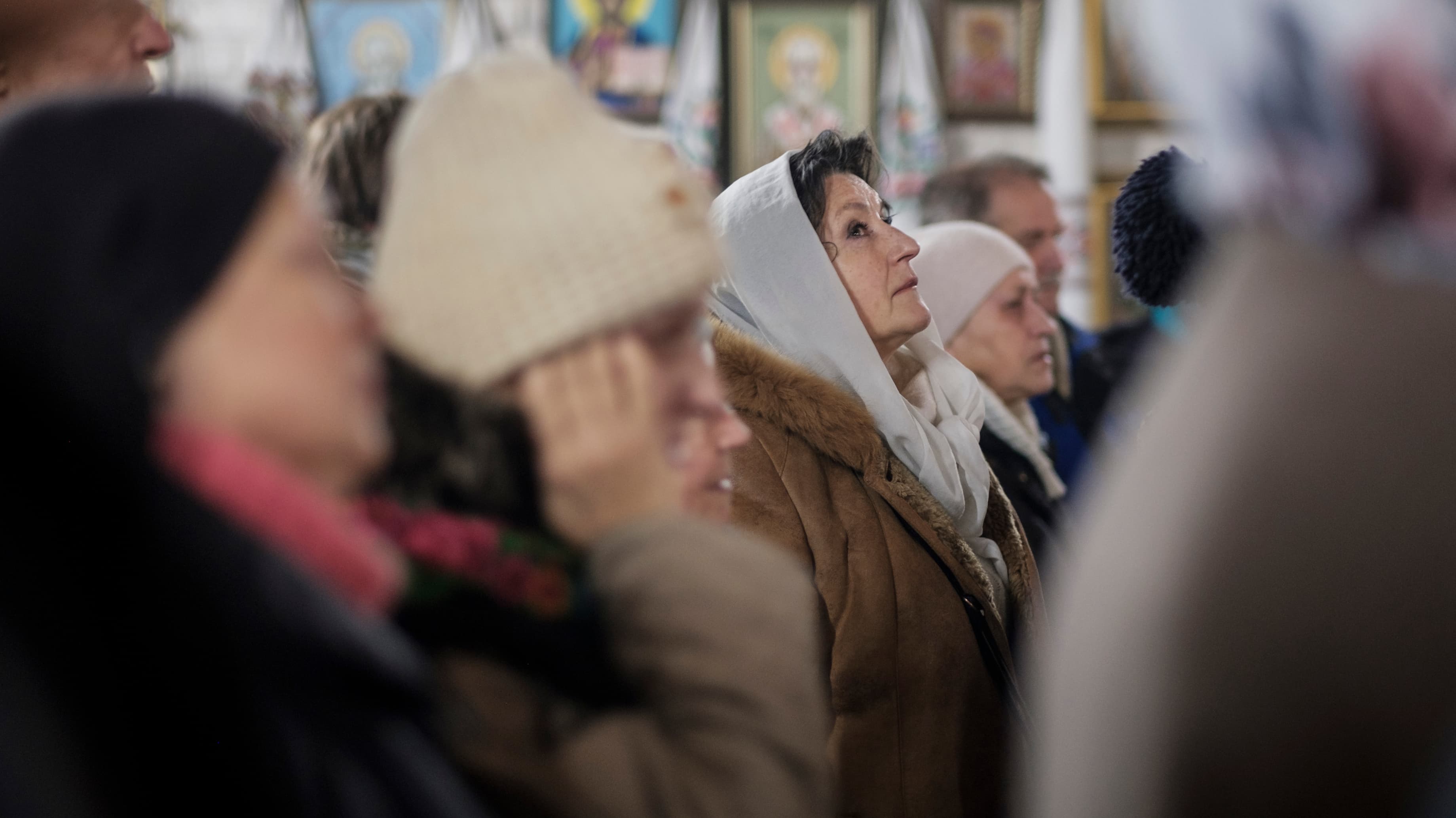 A woman looks up while praying in church.
