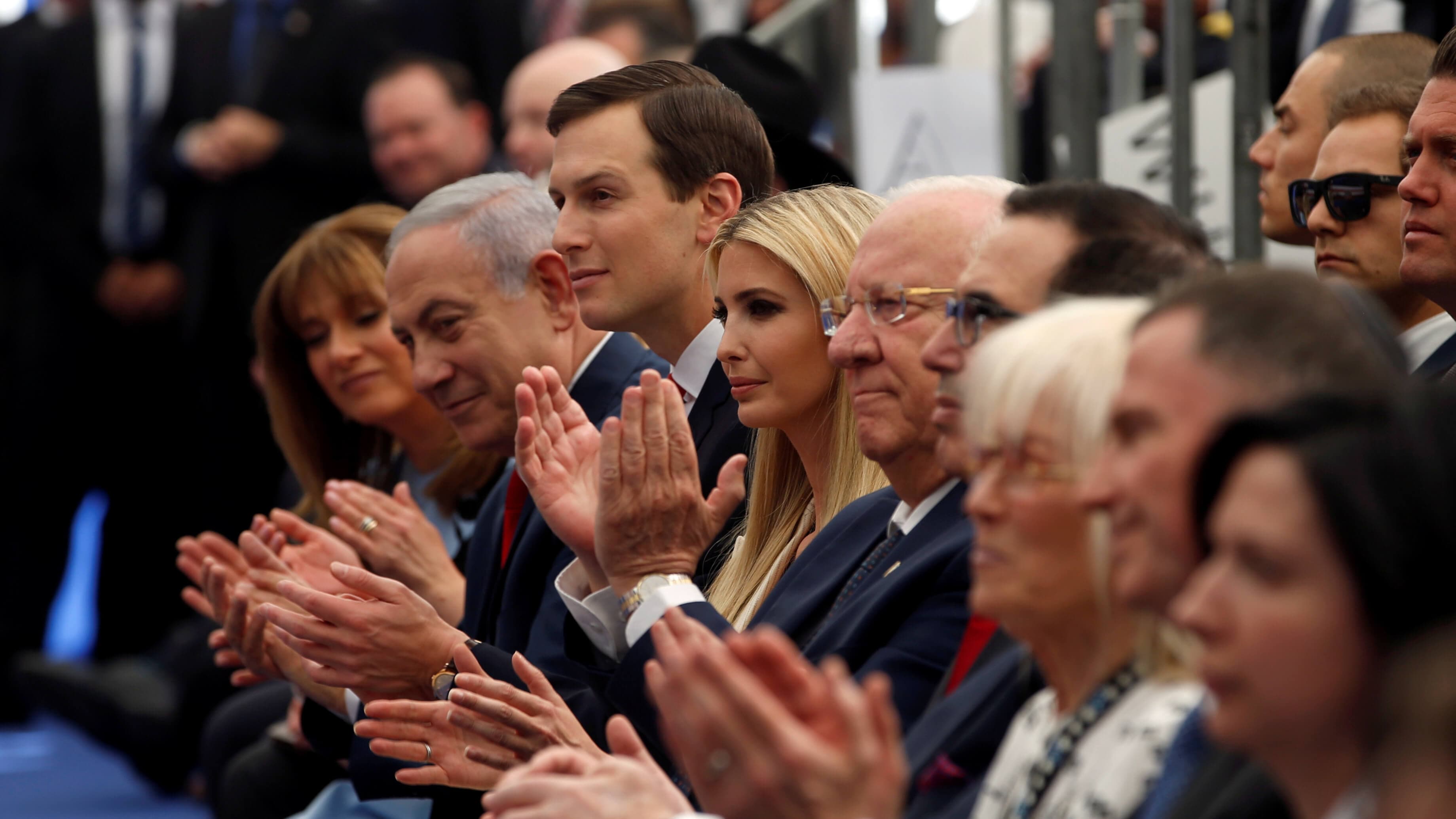 A row of seated politicians clapping.