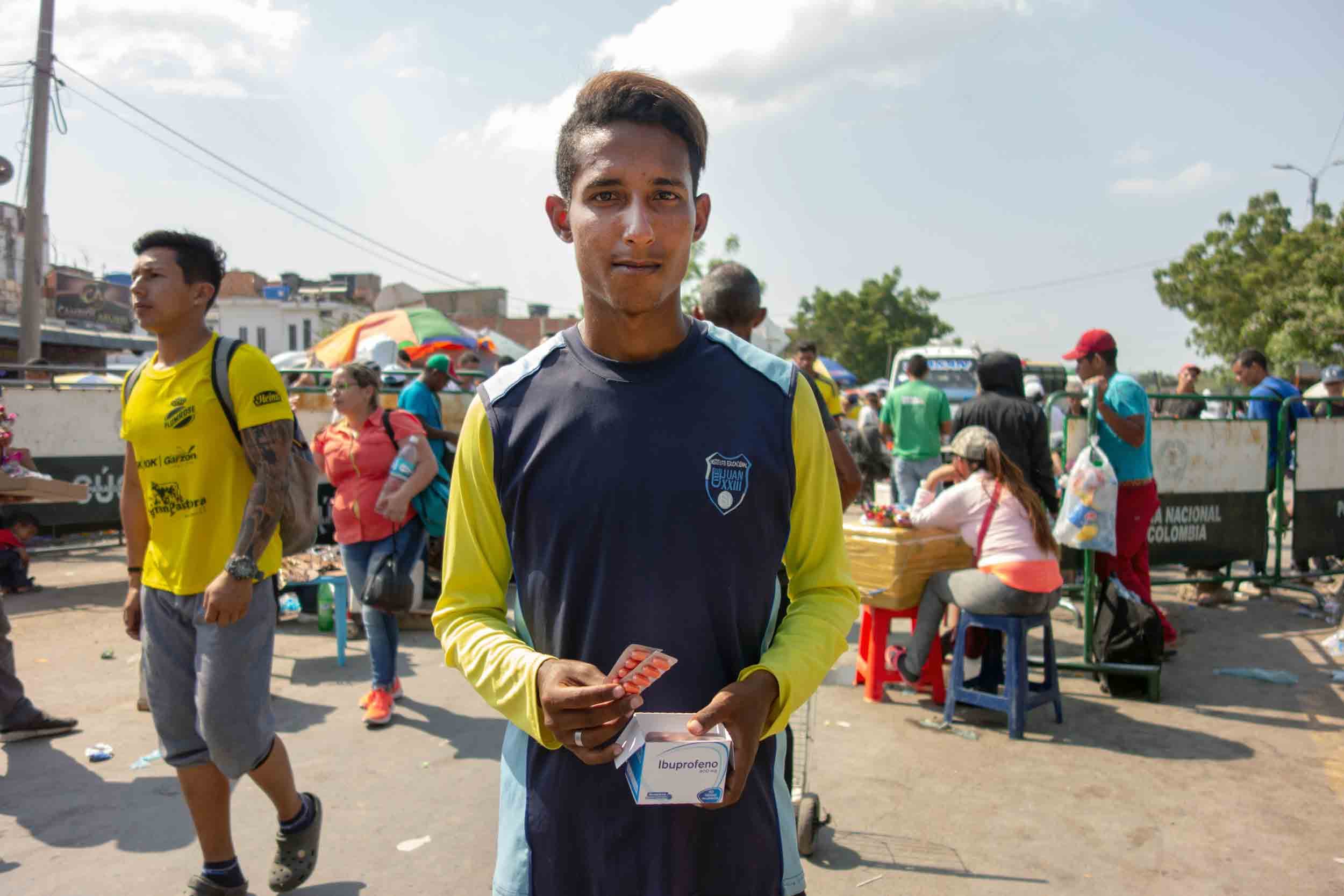 A young man wearing a sports jersey sells medicine tablets on the street.