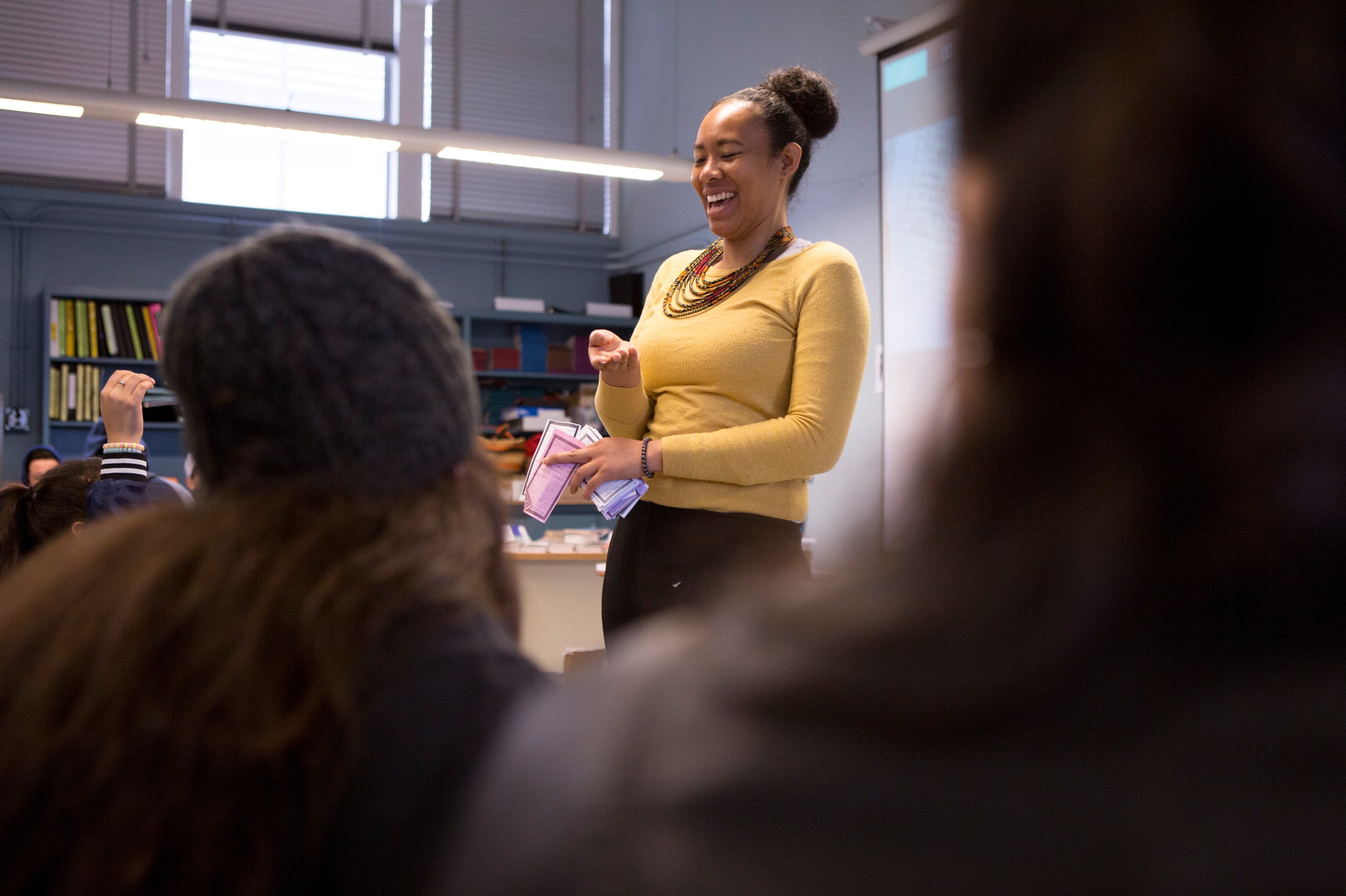 A teacher stands in front of the classroom. She's laughing.